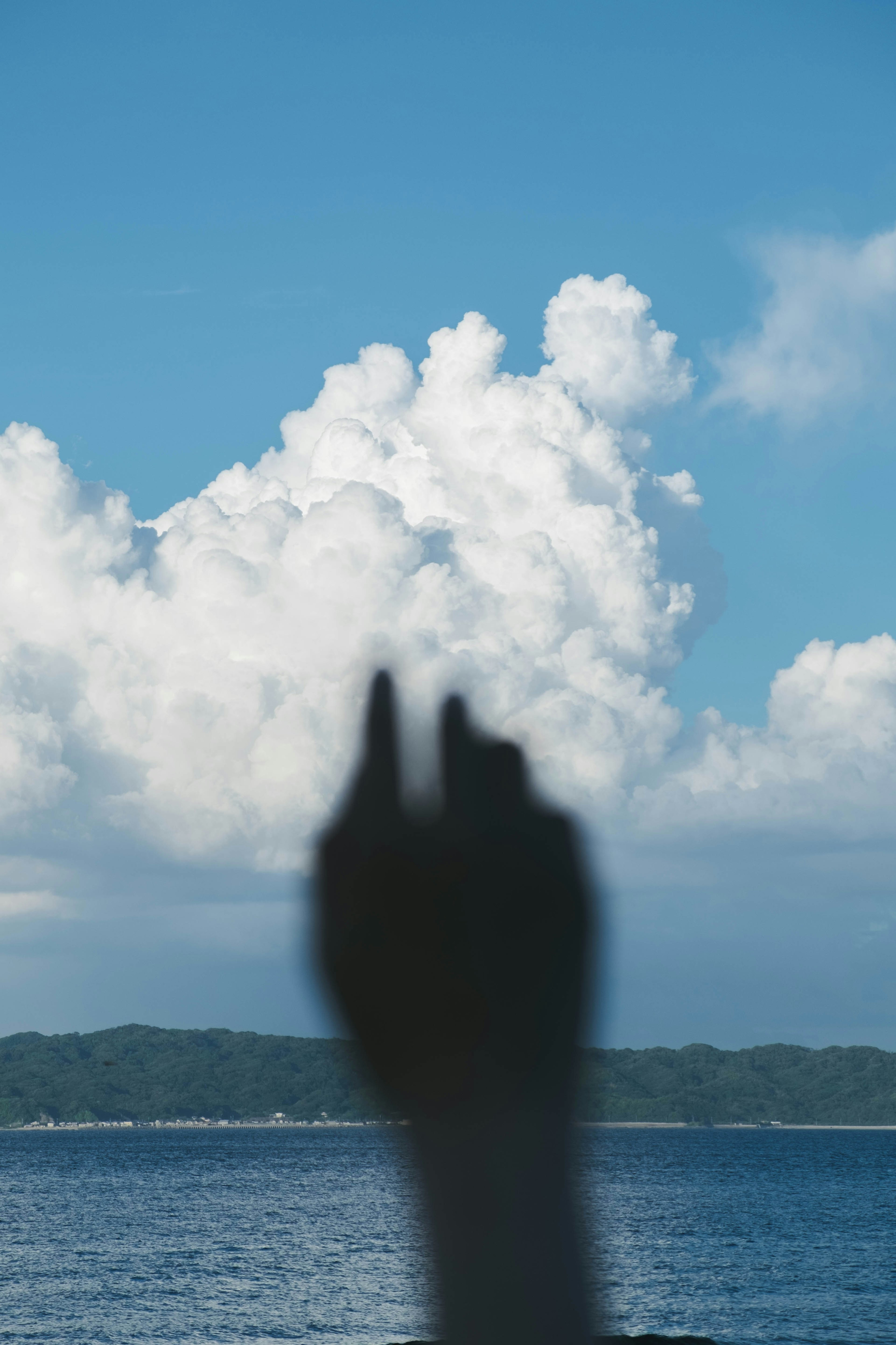 青い空と雲を背景にした手のシルエット