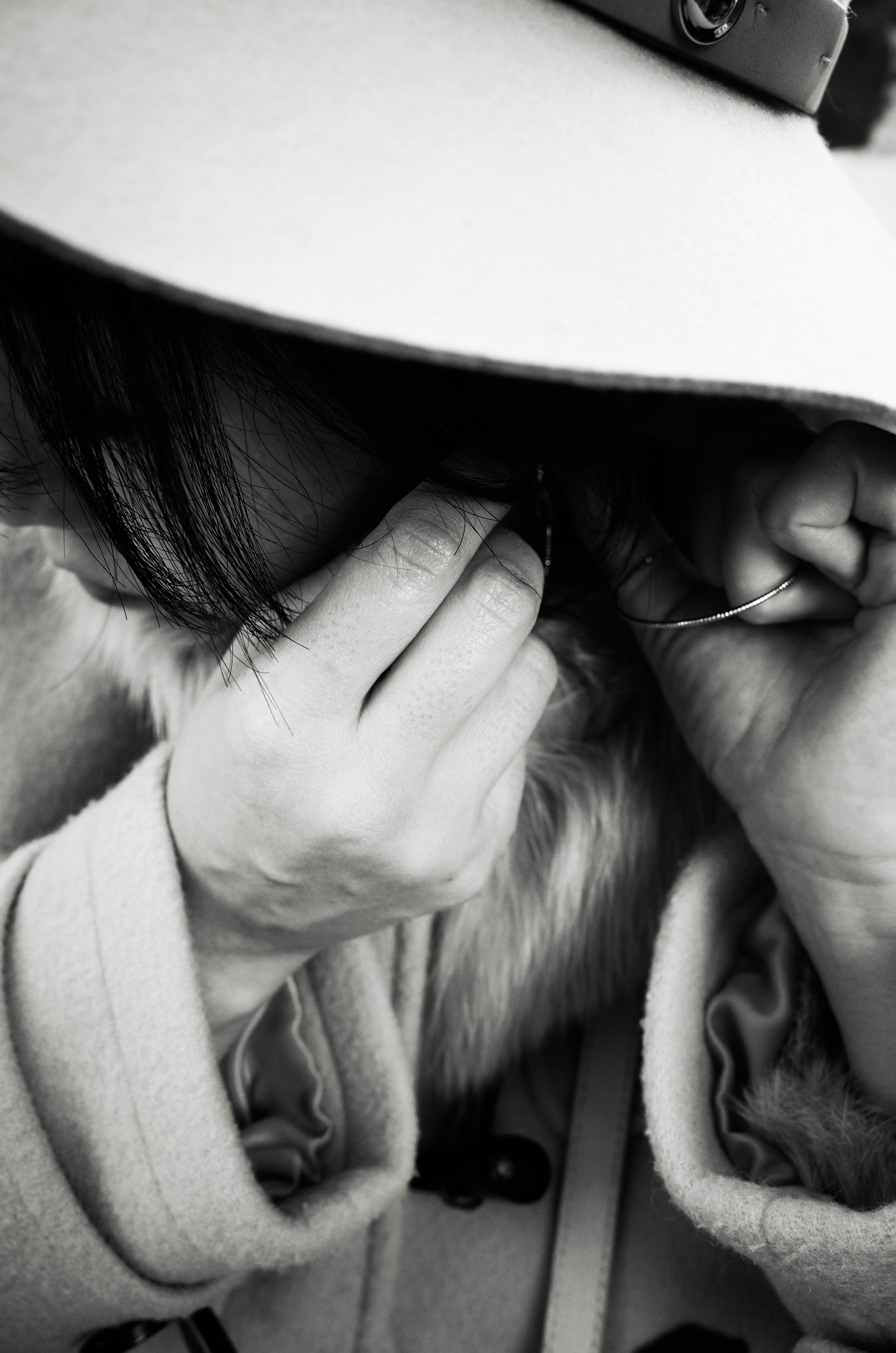 A woman wearing a large hat putting on an earring