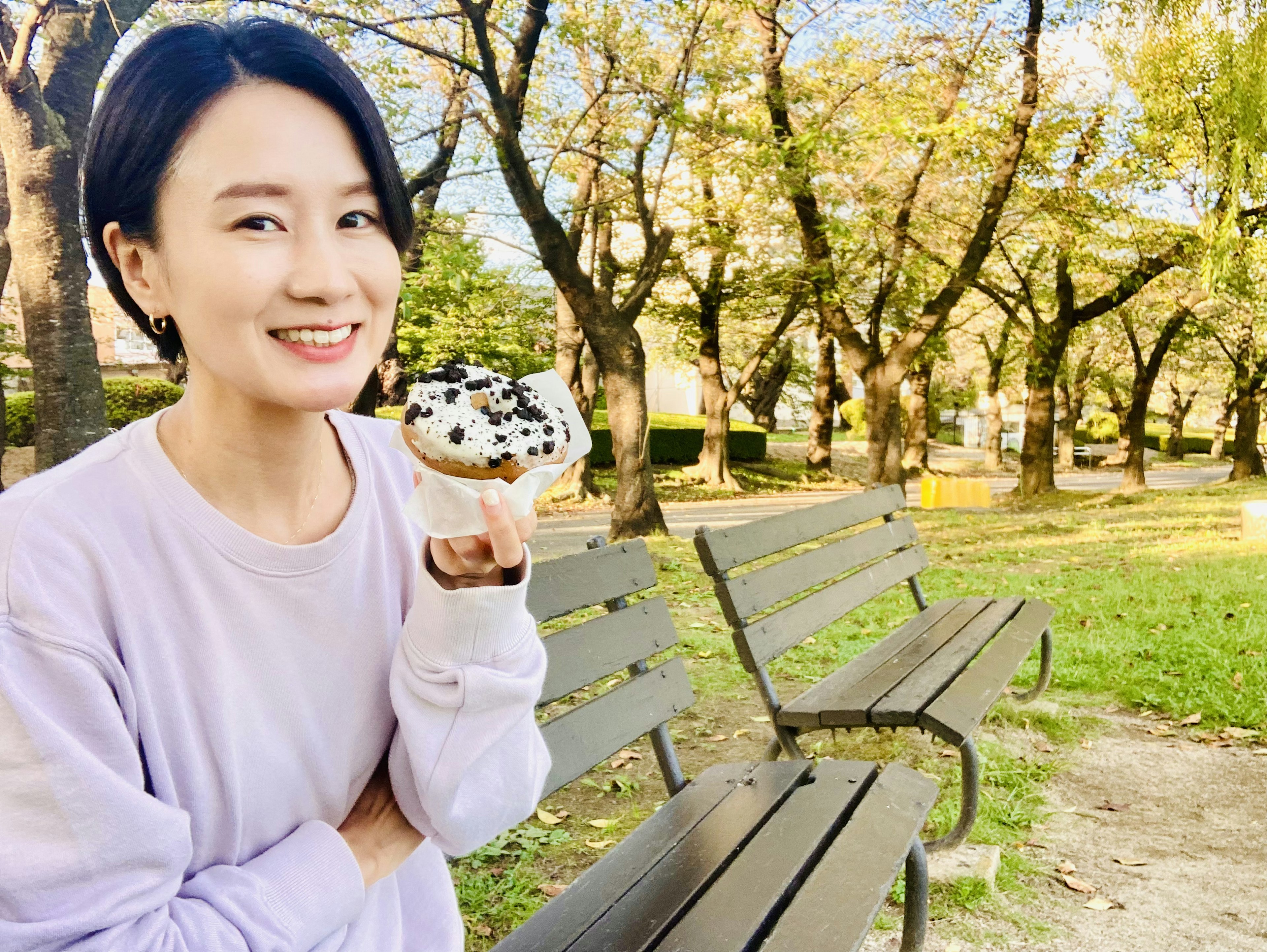 公園でお菓子を持つ女性の笑顔の写真