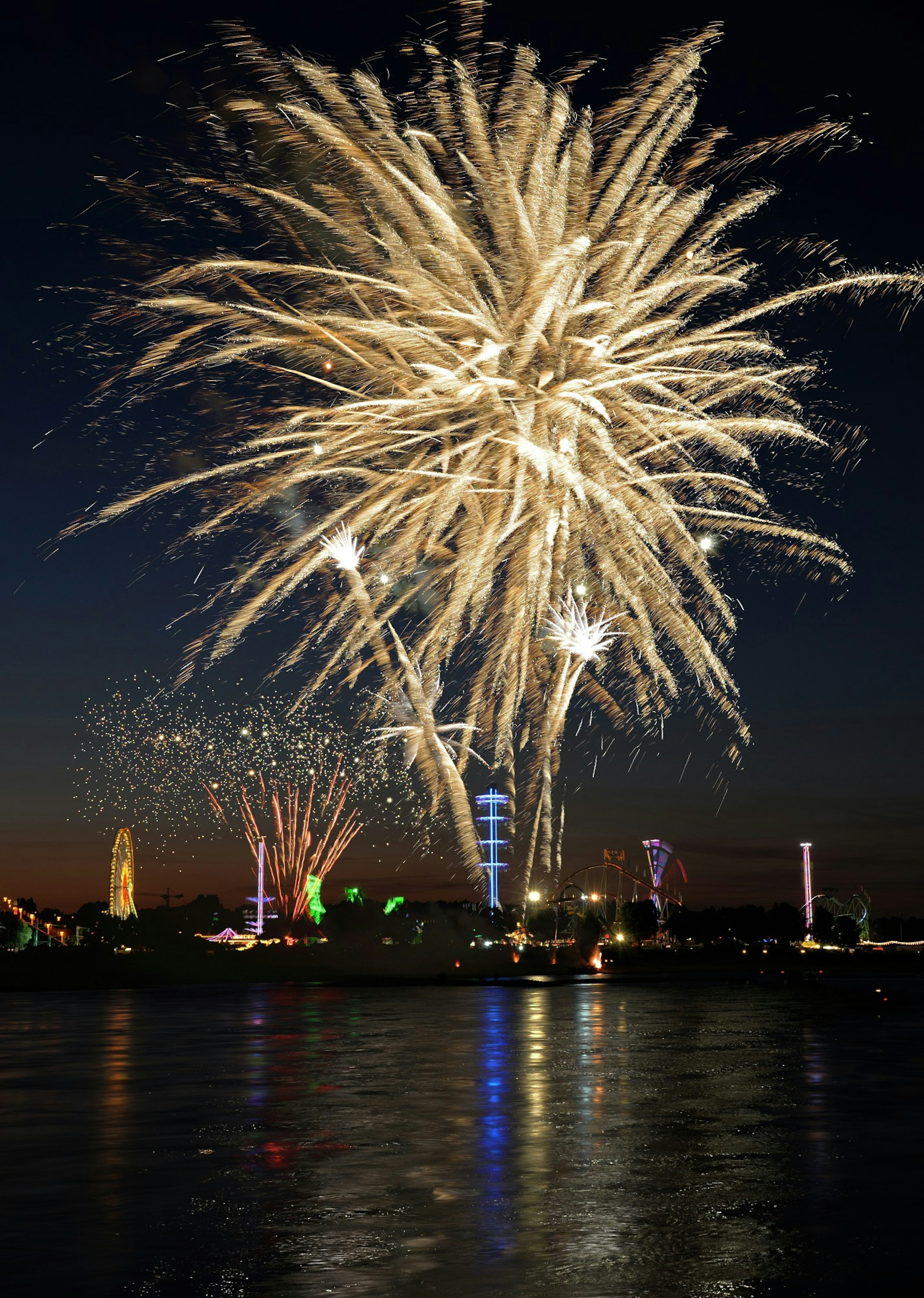 Fuegos artificiales coloridos estallando en el cielo nocturno con reflejos en el agua