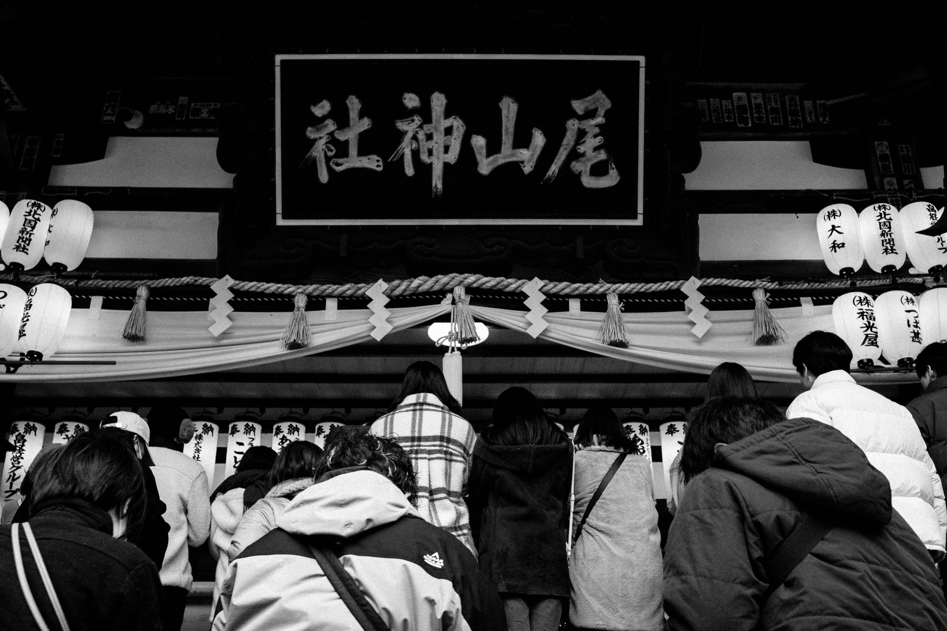 参拝者が神社の前で祈りを捧げているモノクロの写真