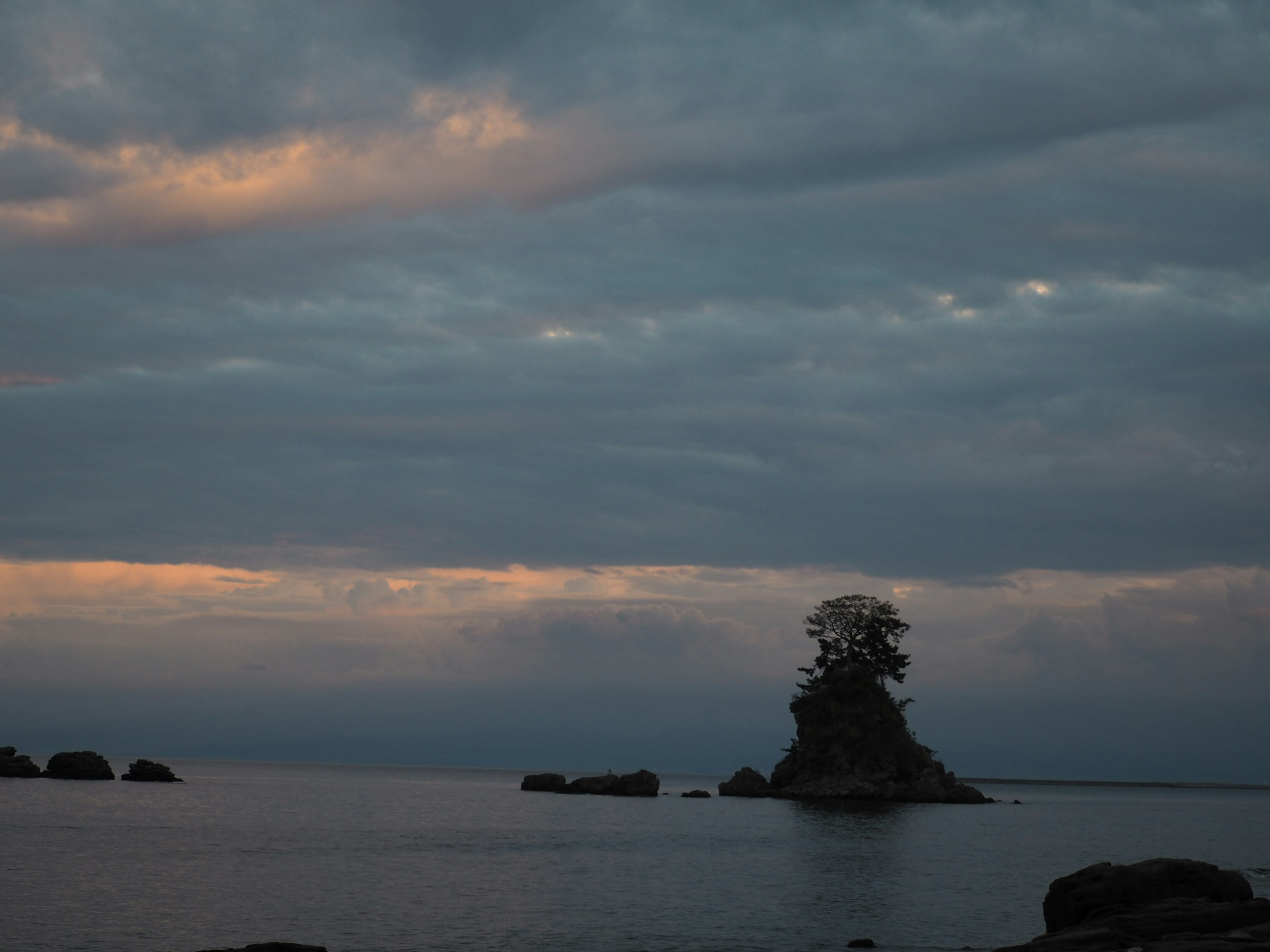 夕暮れ時の静かな海に浮かぶ小さな島と木々