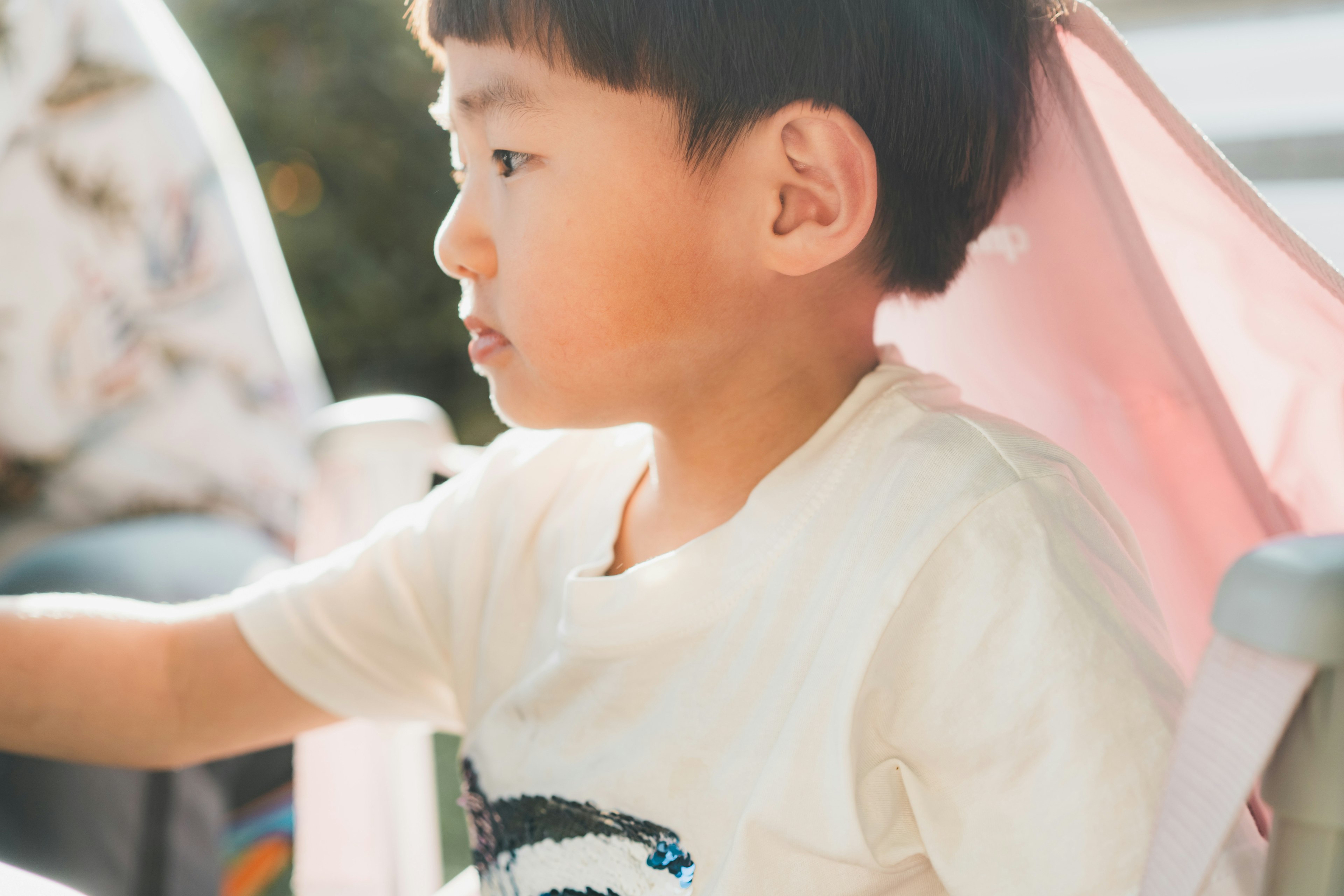 子供が椅子に座っている横顔の写真 明るい色合いと柔らかな光が特徴