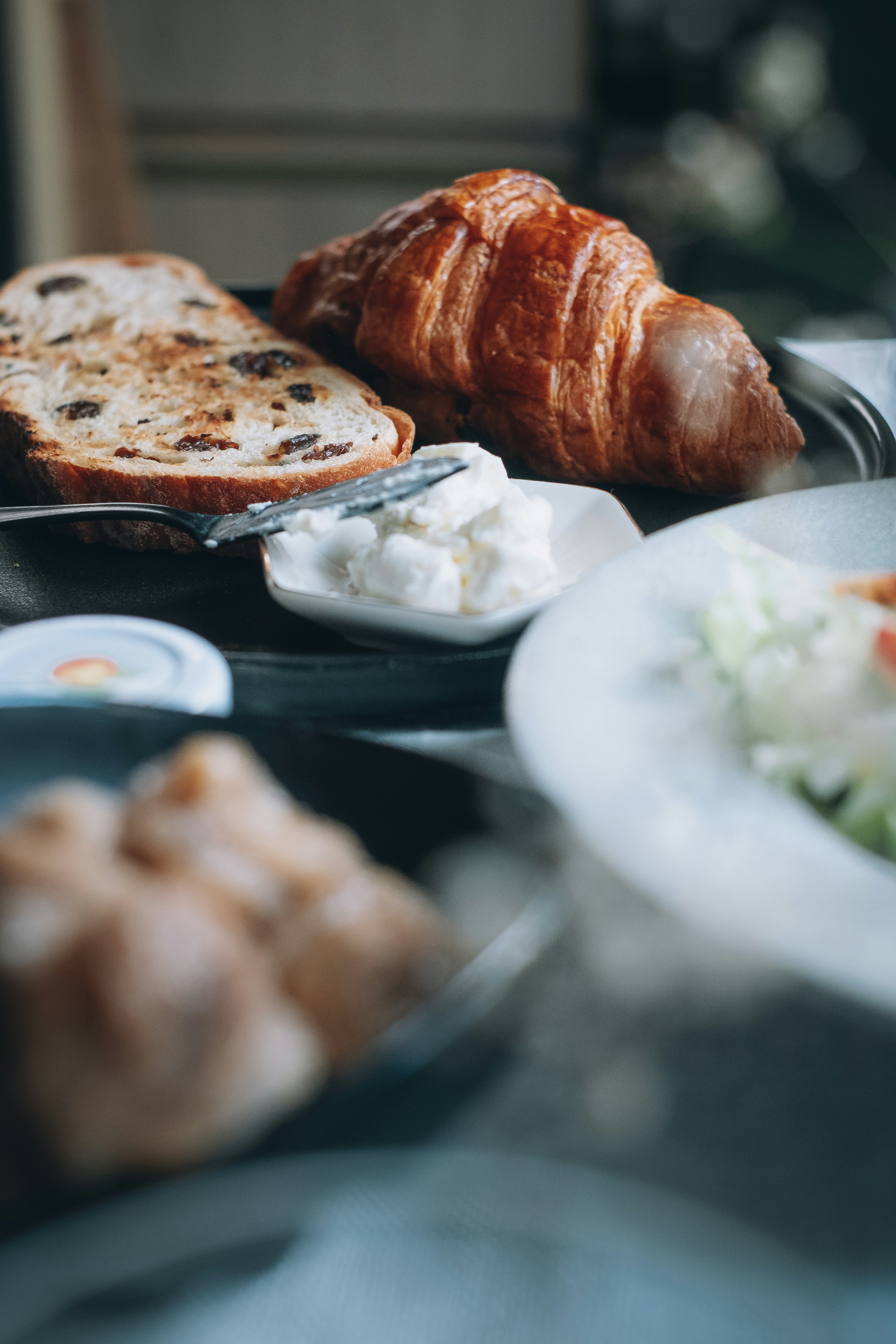 Freshly baked croissant and sweet bread assortment alongside fresh salad and cream