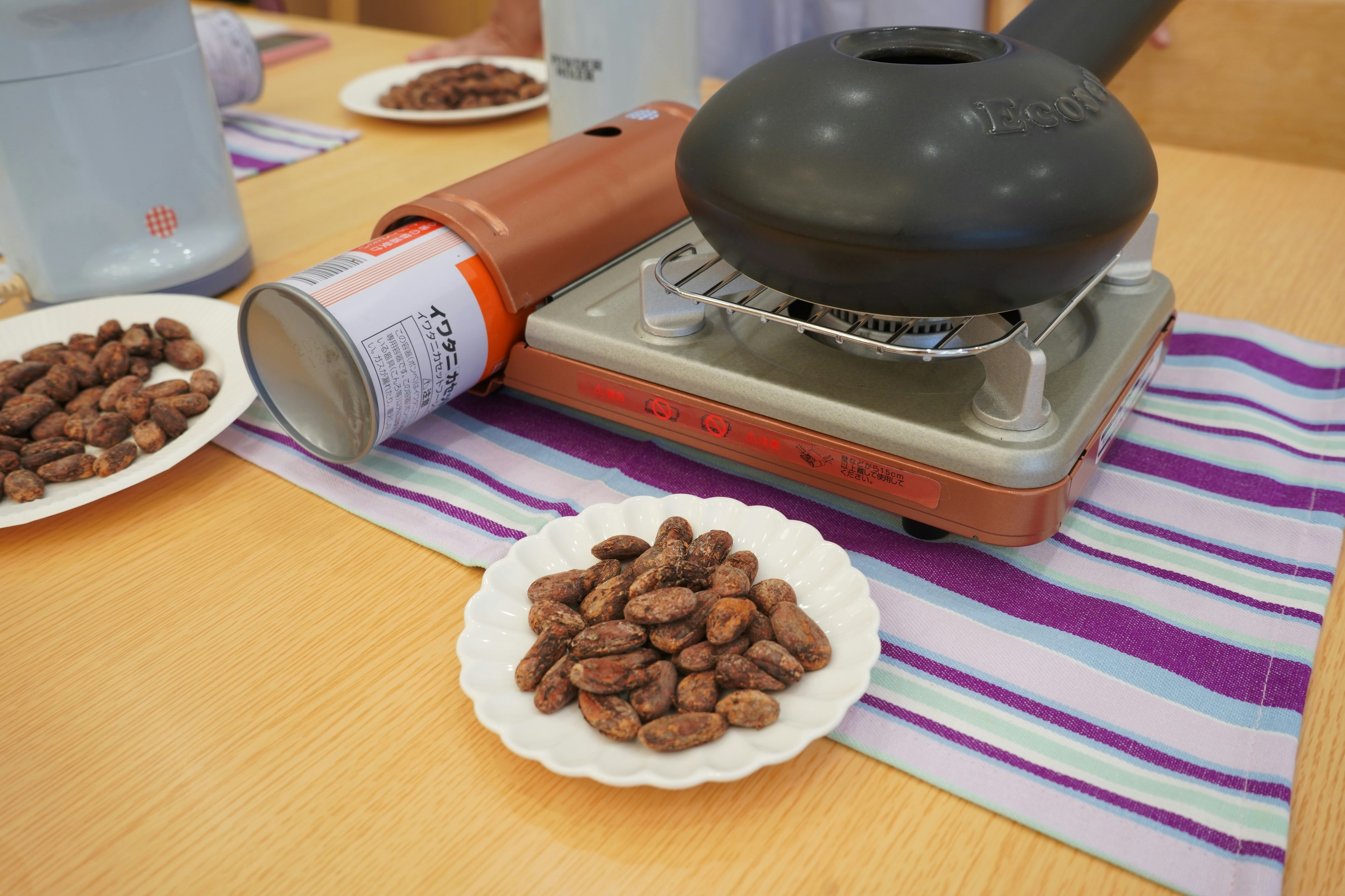 Table with a roasting machine and a plate of cocoa beans