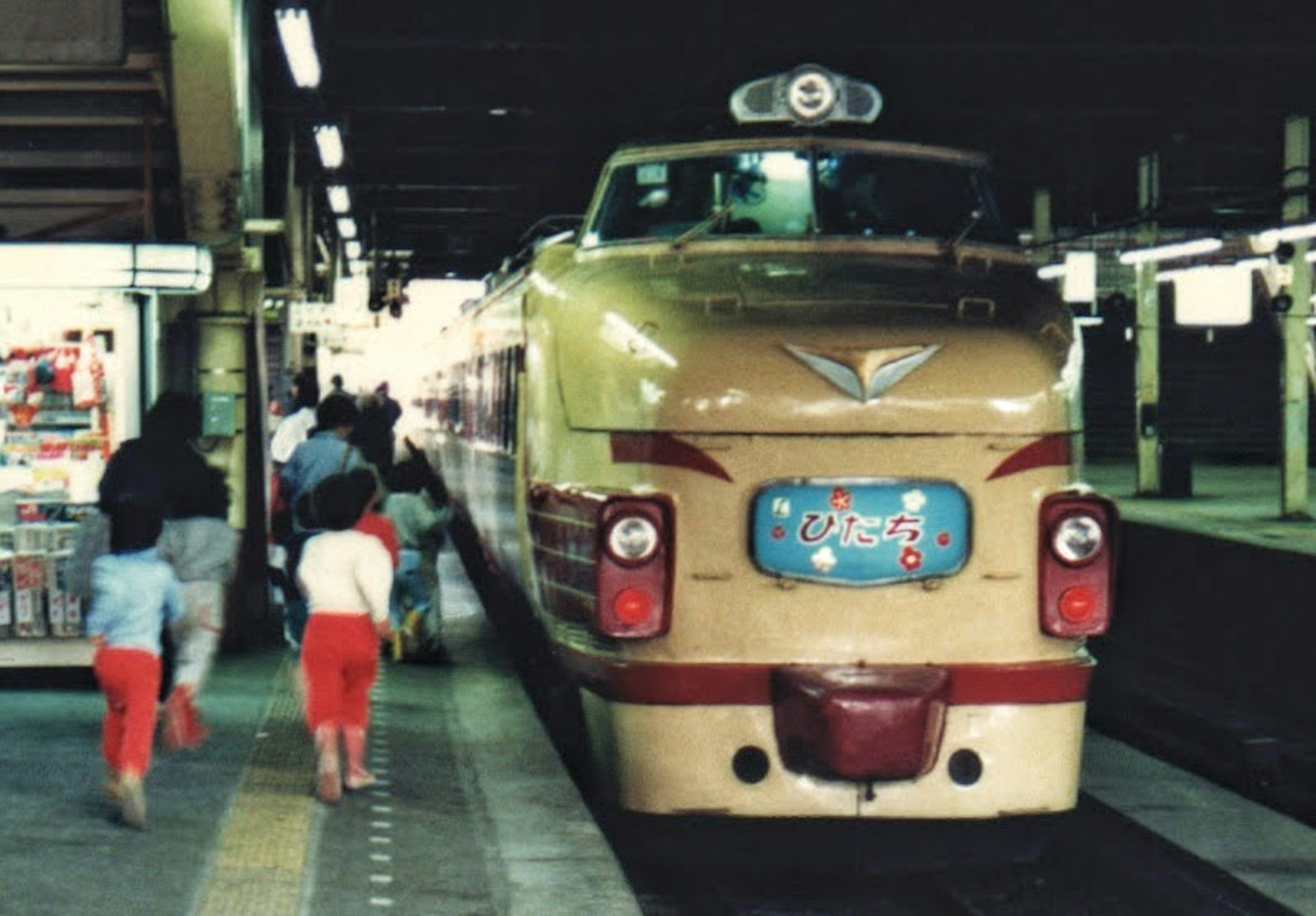 古いデザインの列車が駅に停車している子供たちが近くを歩いている