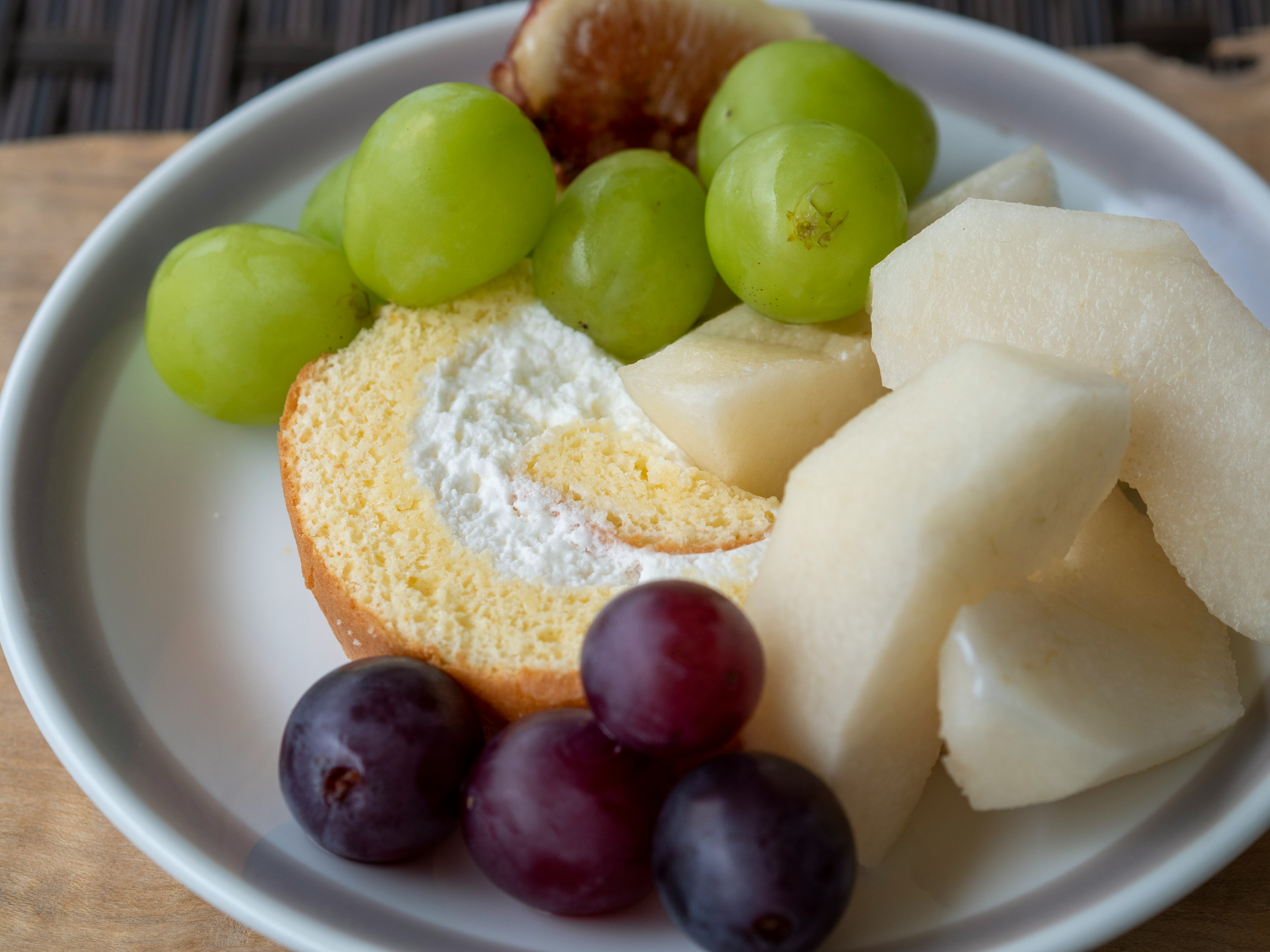 Torta di spugna con crema e frutta assortita tra cui uva e melone