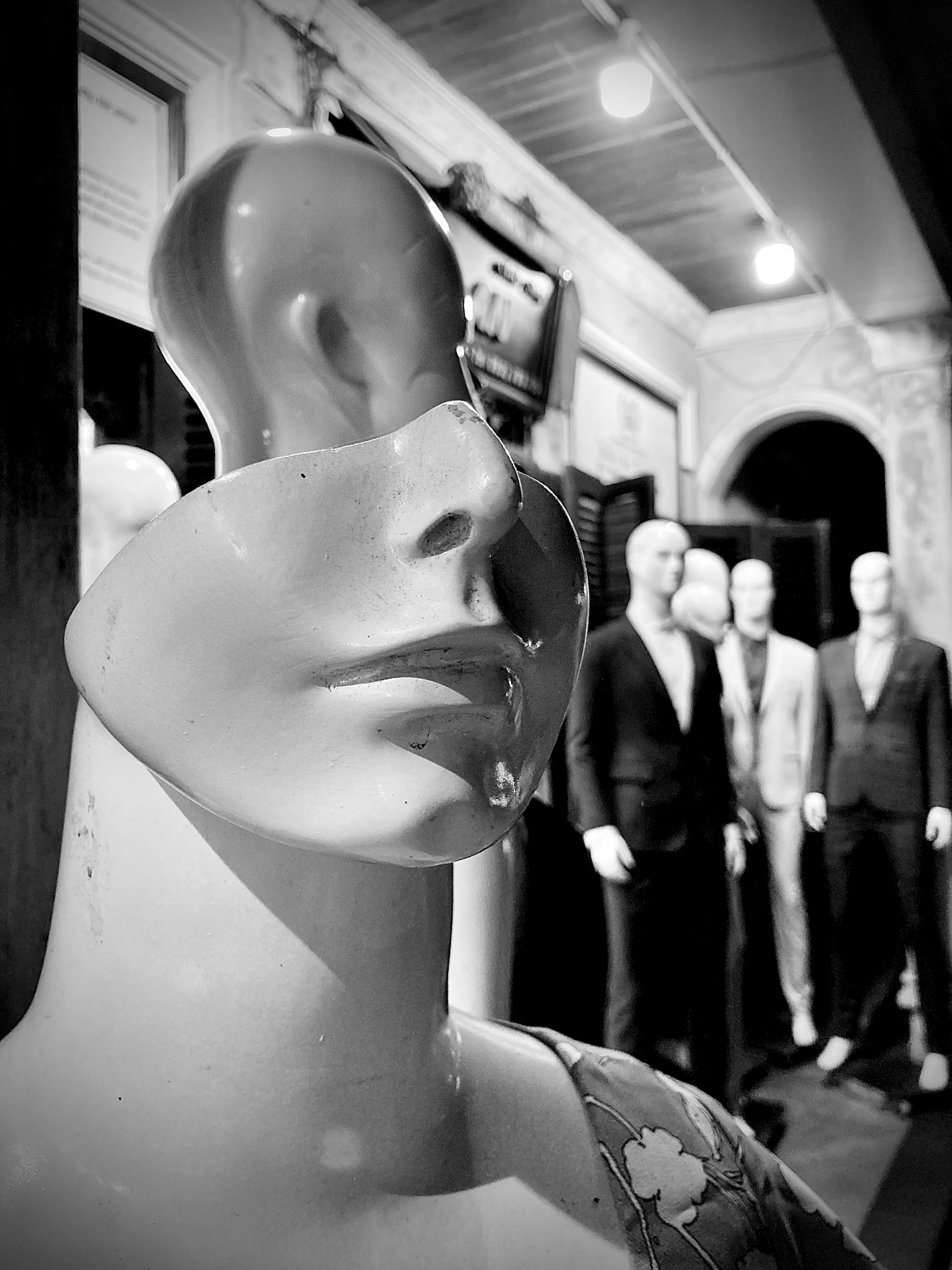 Gros plan sur un visage de mannequin blanc avec une caractéristique unique et plusieurs mannequins en costume en arrière-plan