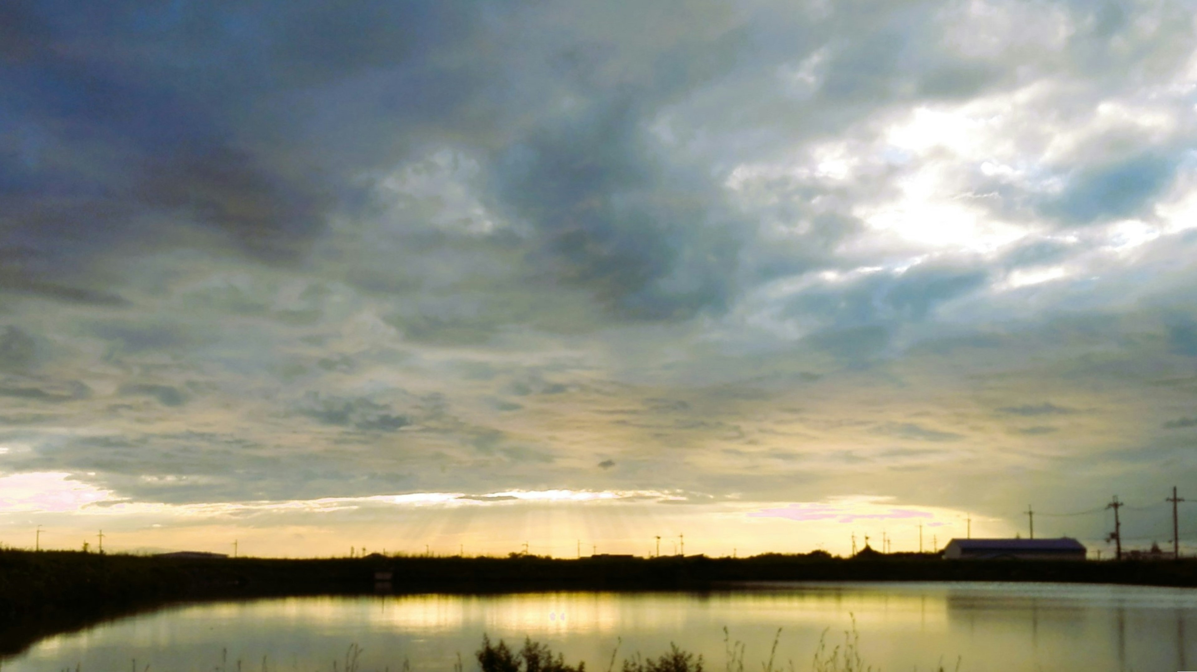 Paisaje de un lago bajo un cielo nublado con reflejos del atardecer