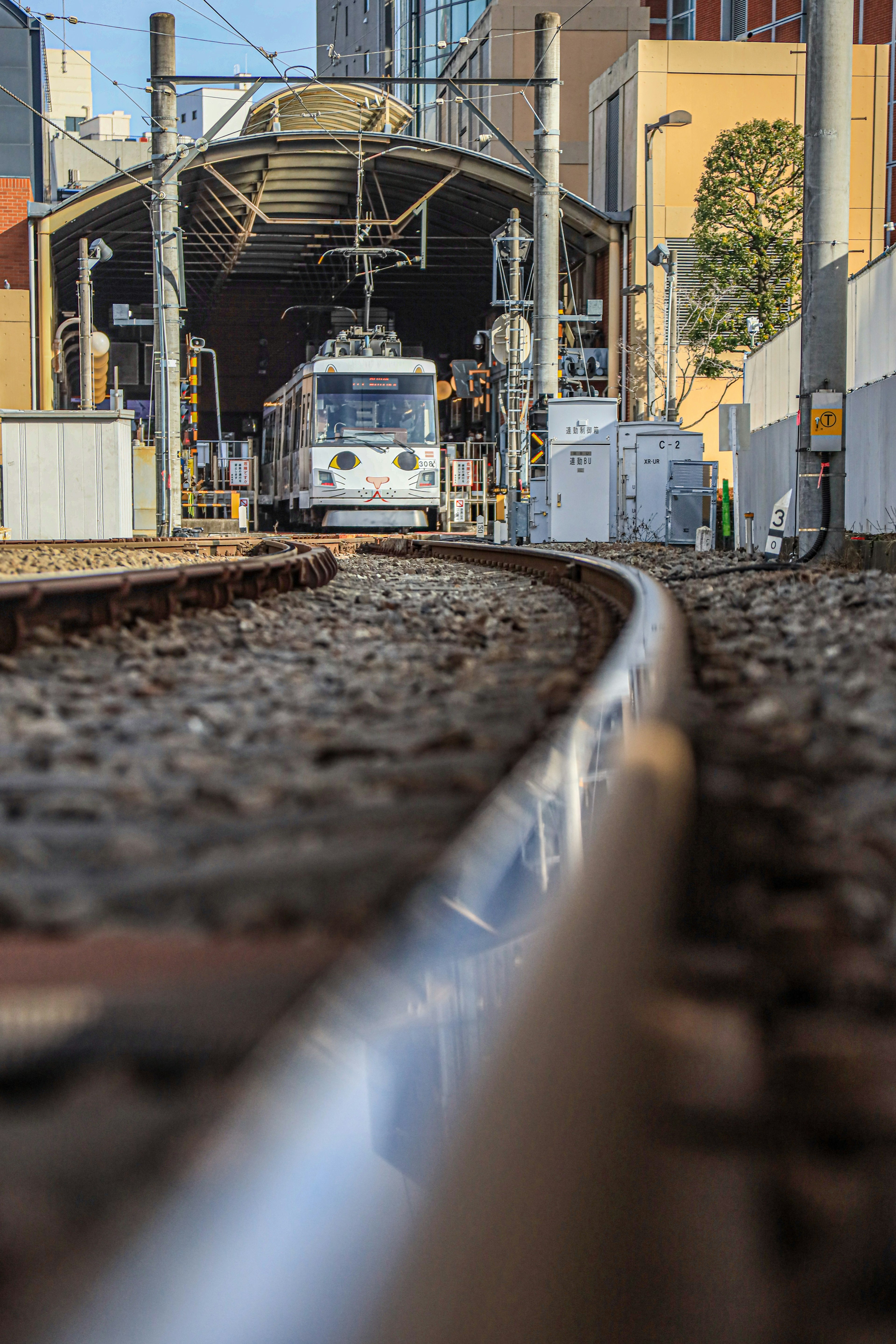 View of a train station with tracks in the foreground and a train approaching in the distance