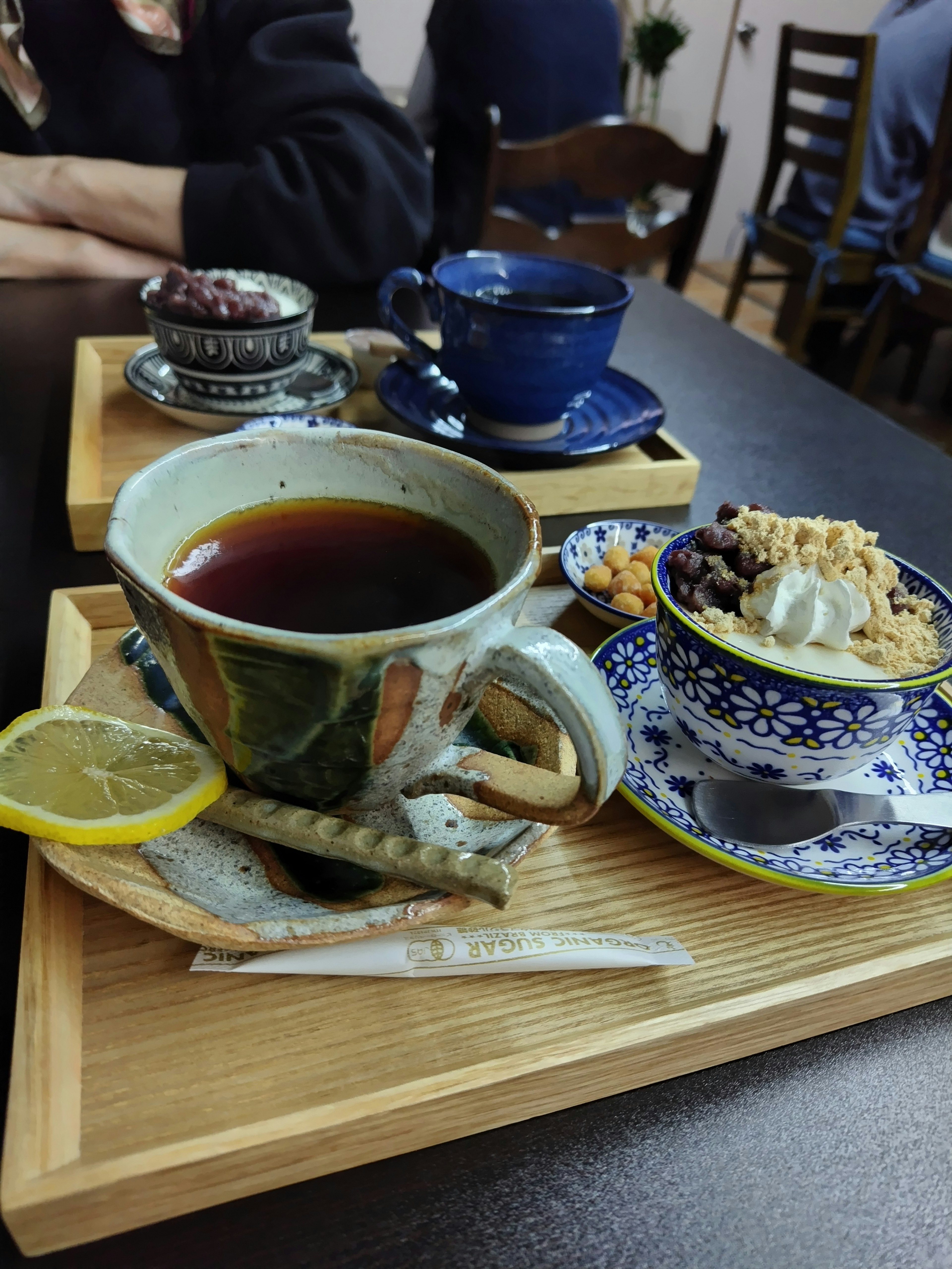 Imagen de una taza de café colorida con dulces dispuestos en una bandeja de madera