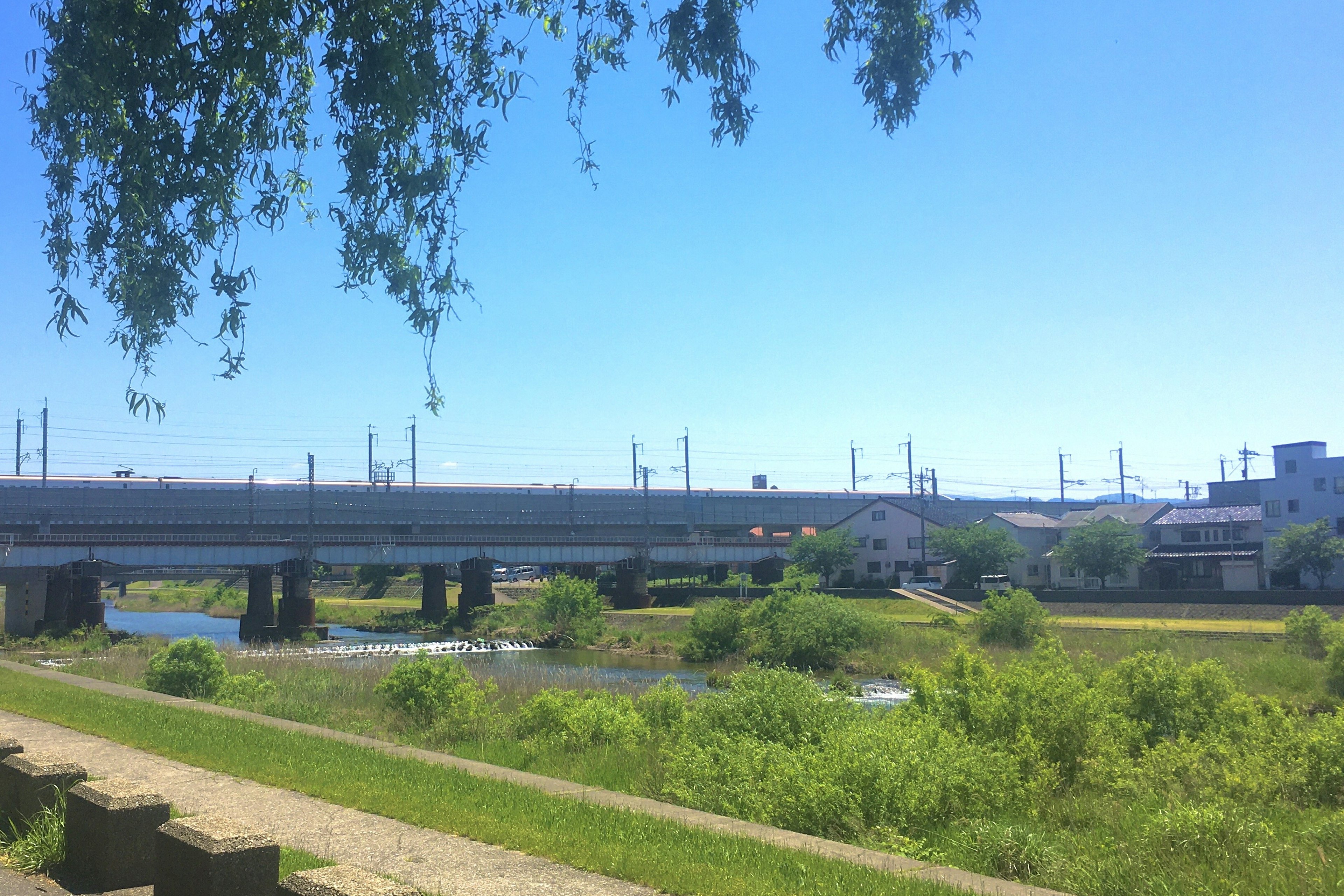 Scenic view of a river and railway bridge under a clear blue sky