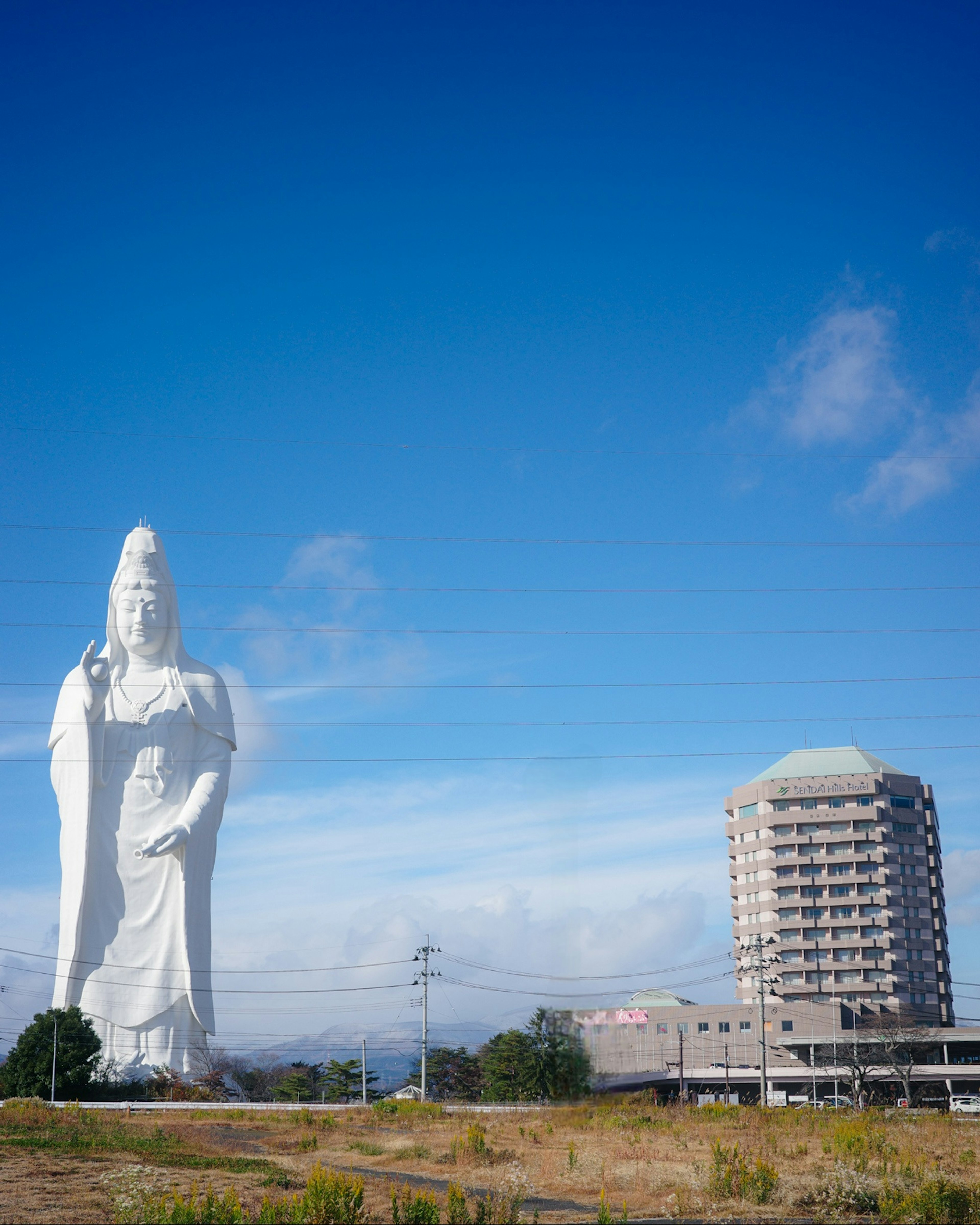 Una grande statua di Kannon si erge sotto un cielo blu chiaro