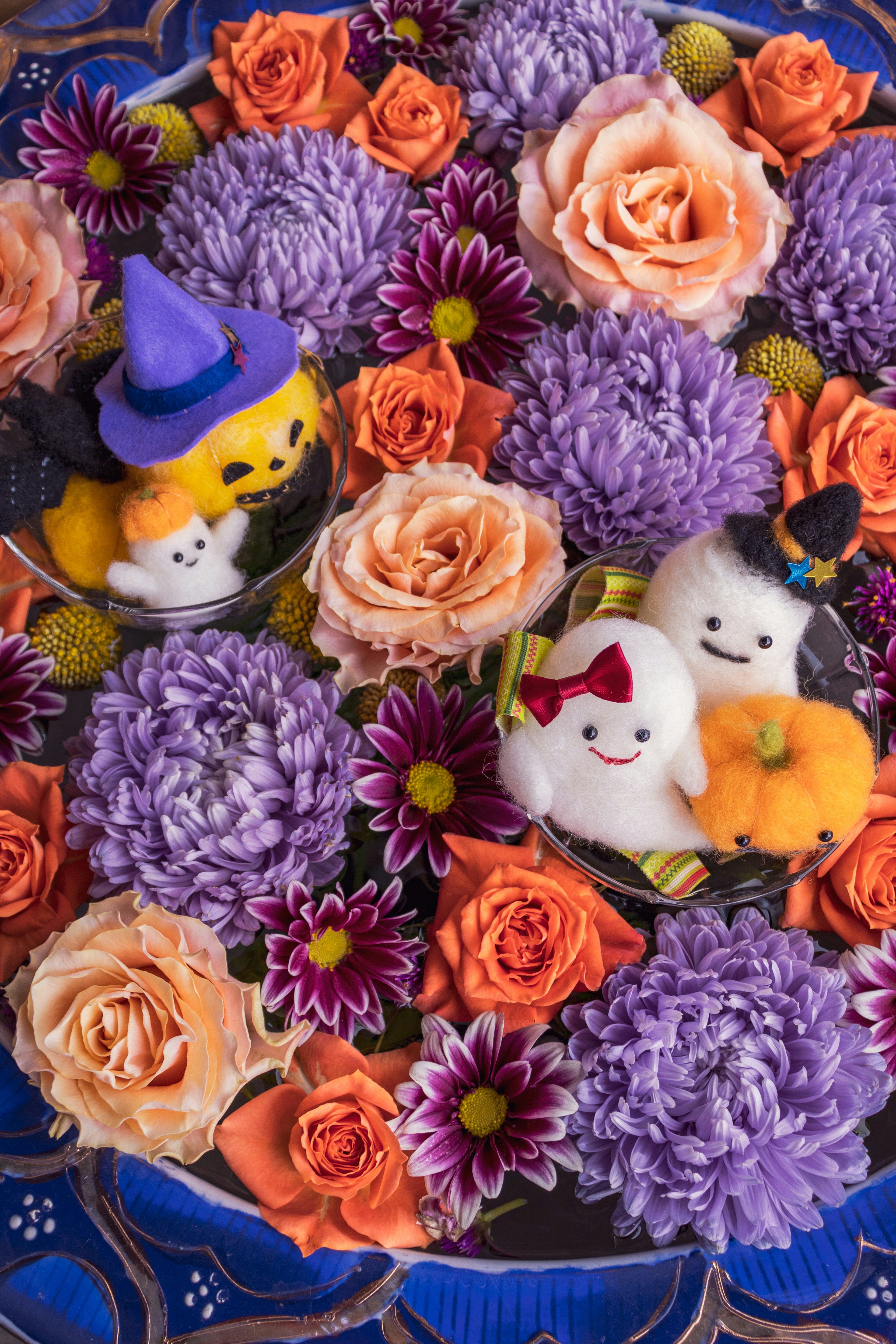 Jouets en peluche d'Halloween entourés de fleurs violettes et oranges