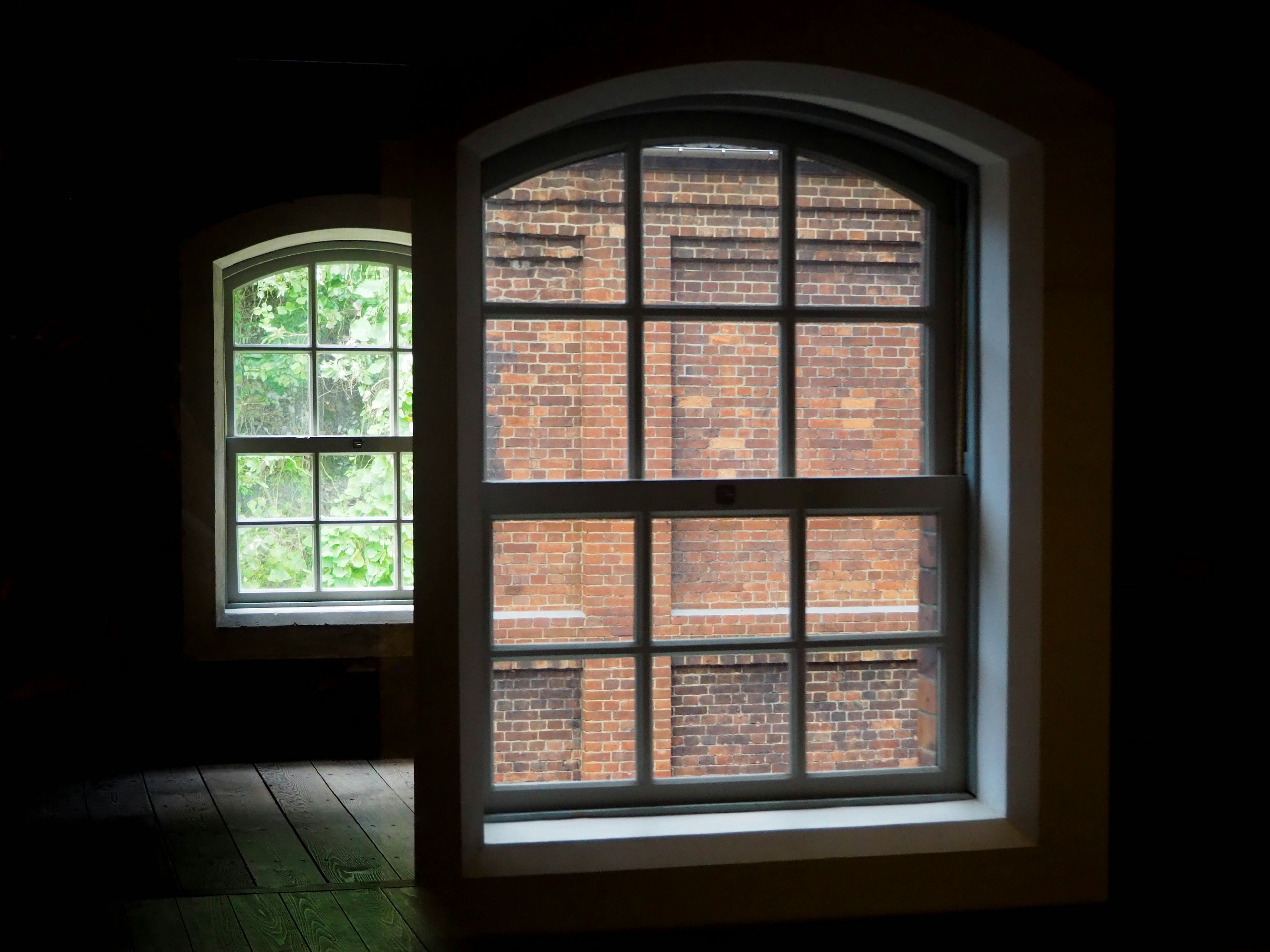 Interior view featuring a large window and a smaller window with a brick wall visible