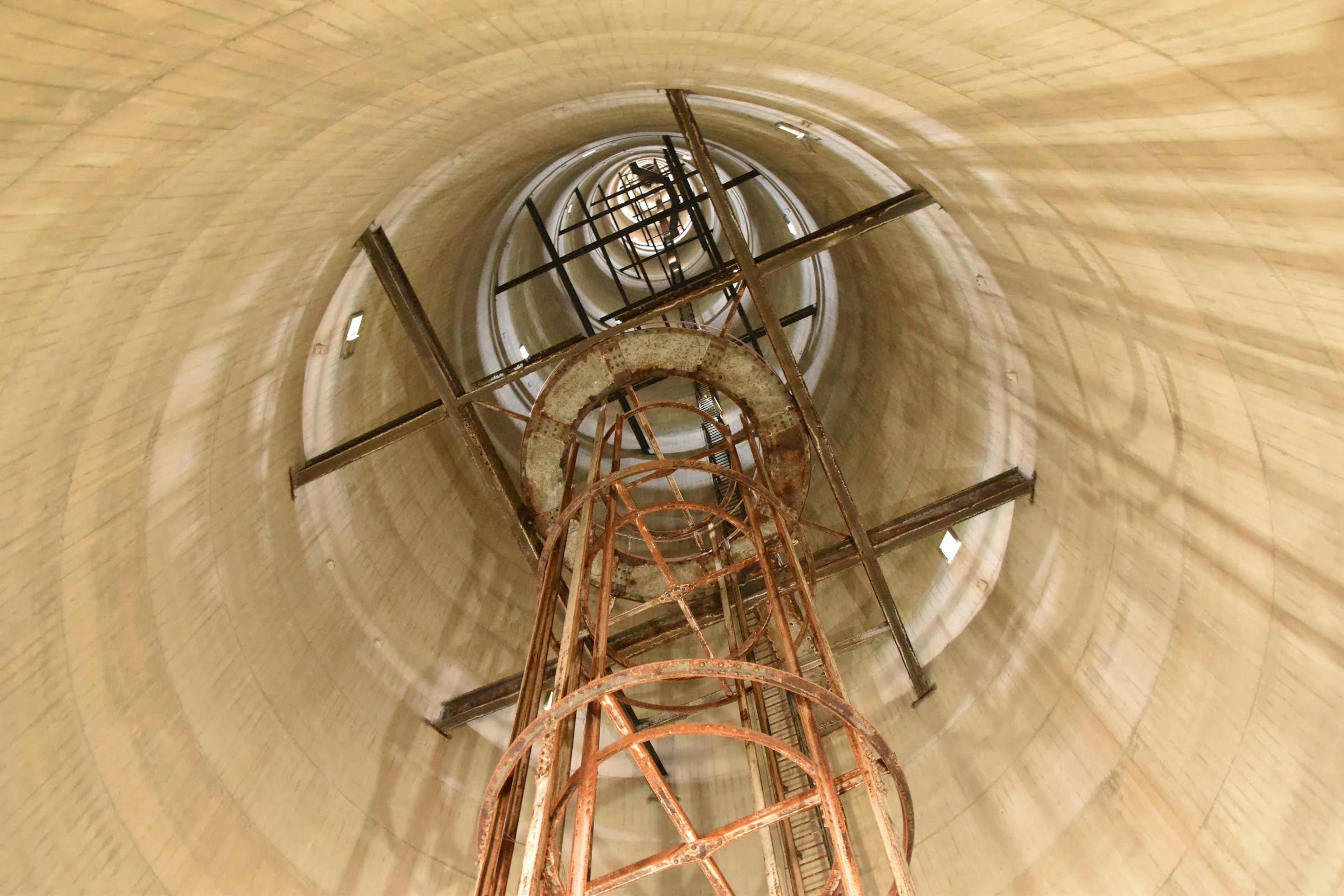 View looking up inside a cylindrical tower showing a metal staircase