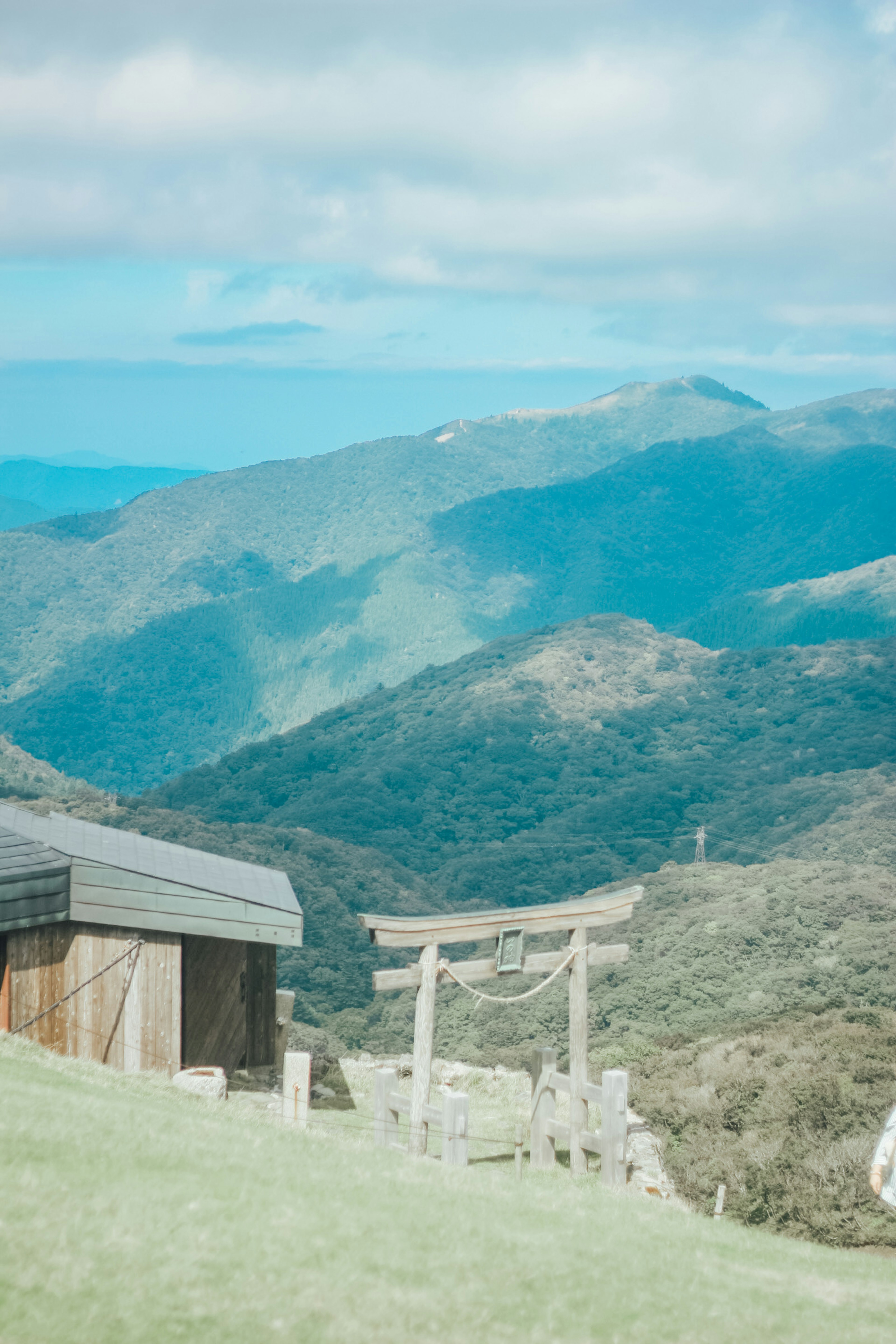 Scenic view of blue mountains with a small building and a torii gate