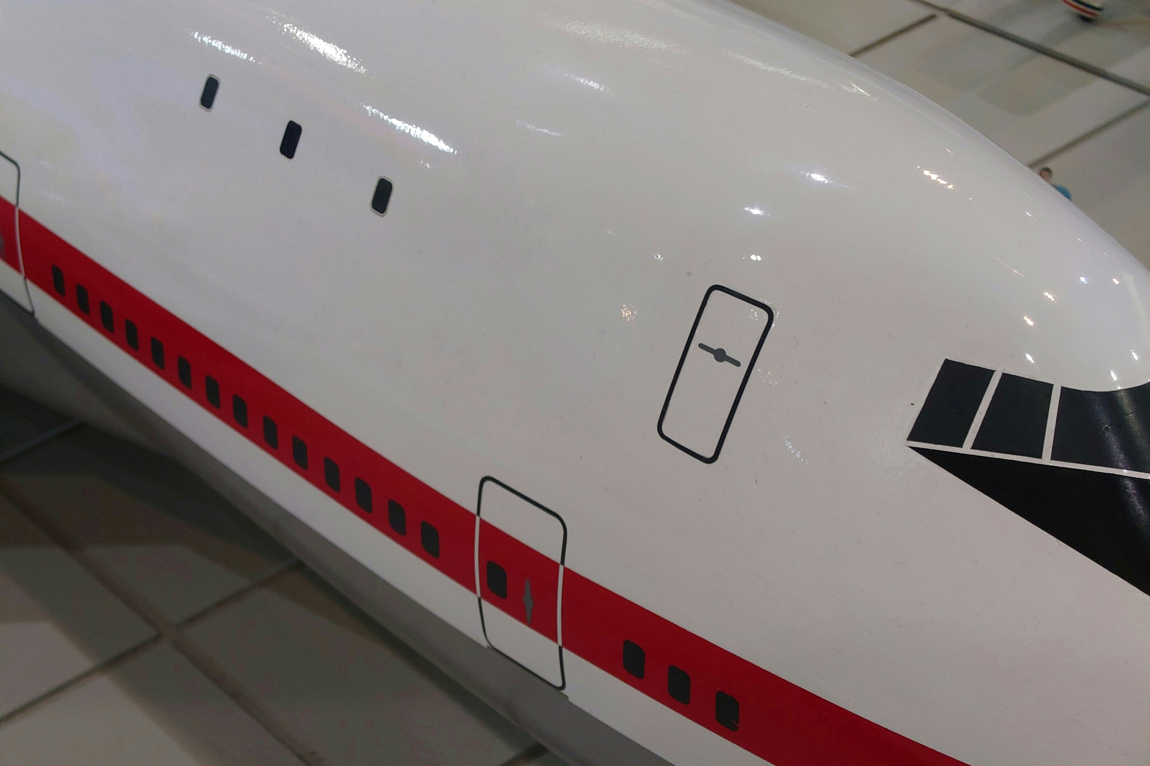 Airplane fuselage with a white body featuring red stripes and black window design