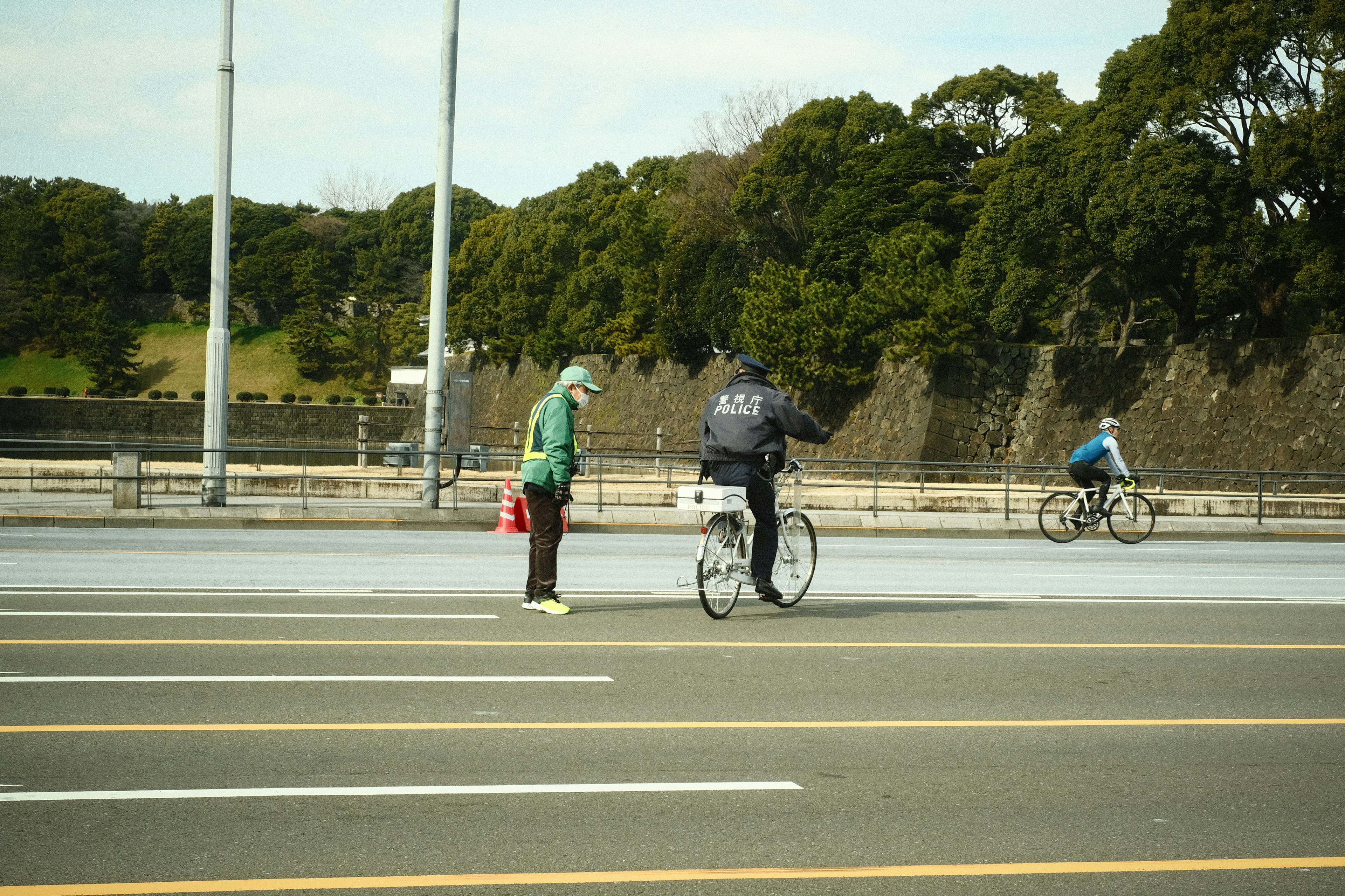 自転車に乗った人と立っている人が公園の近くで会話している様子