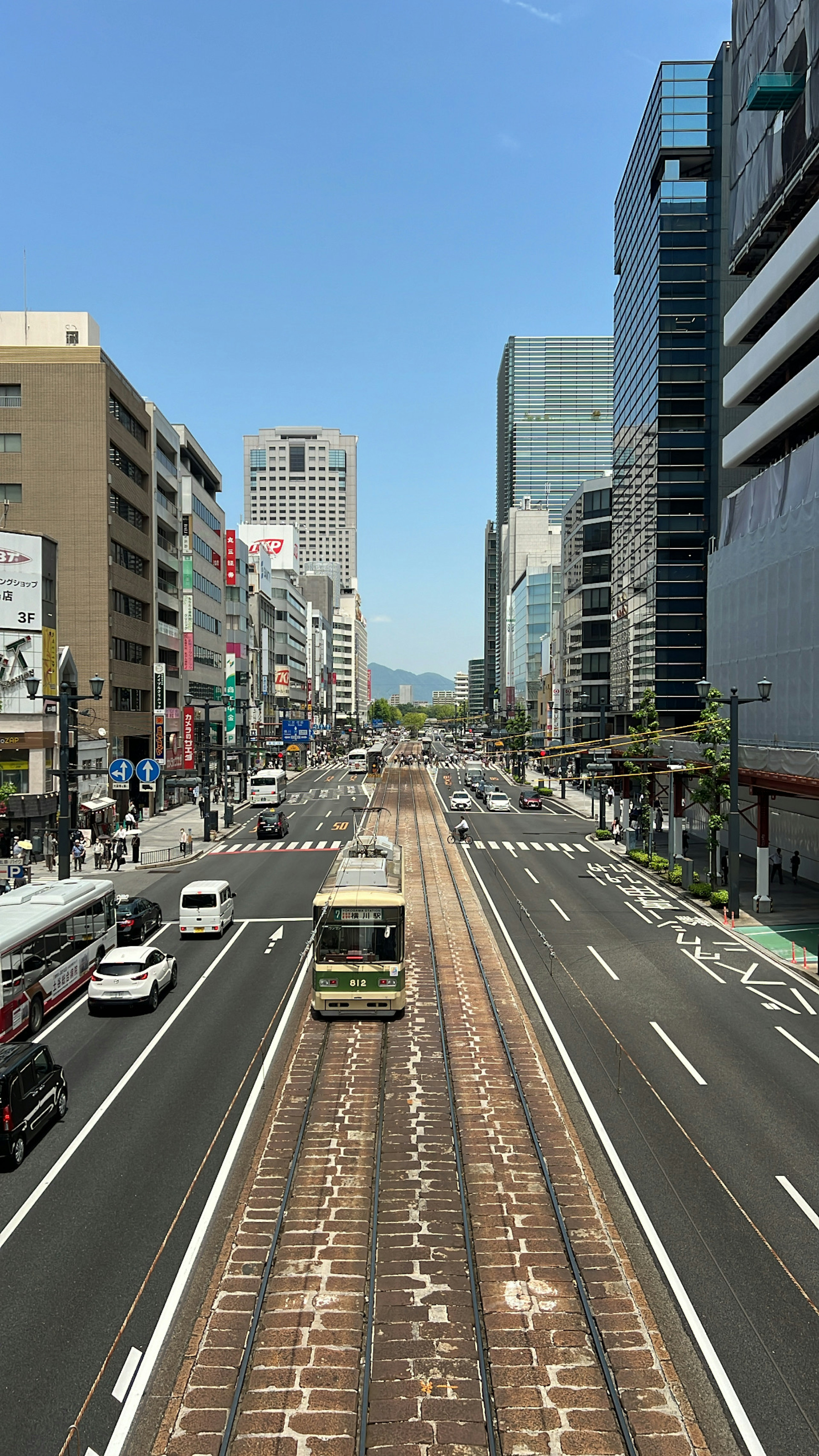 Städtische Straße mit Straßenbahngleisen unter einem klaren blauen Himmel