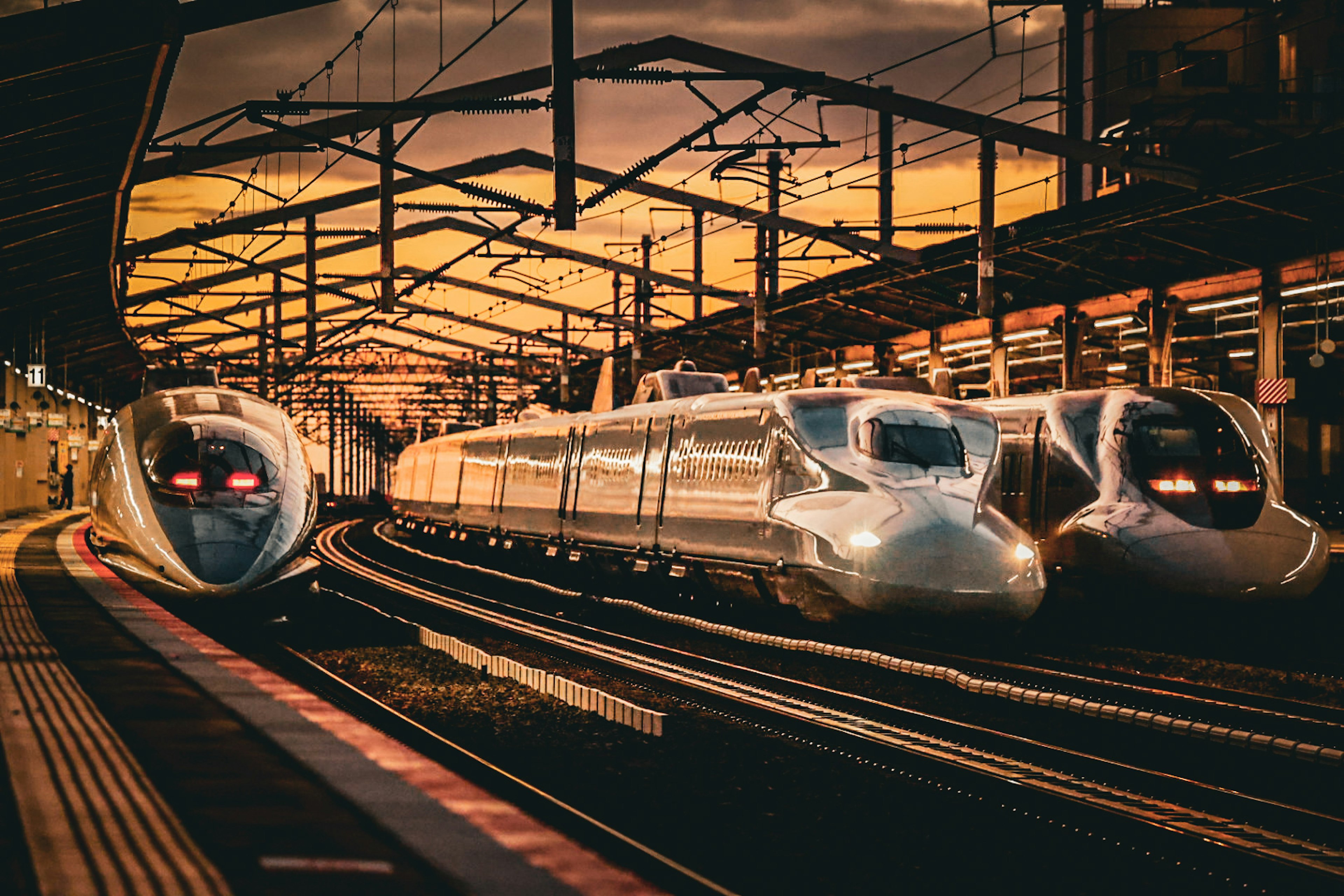 Shinkansen trains at a station during sunset