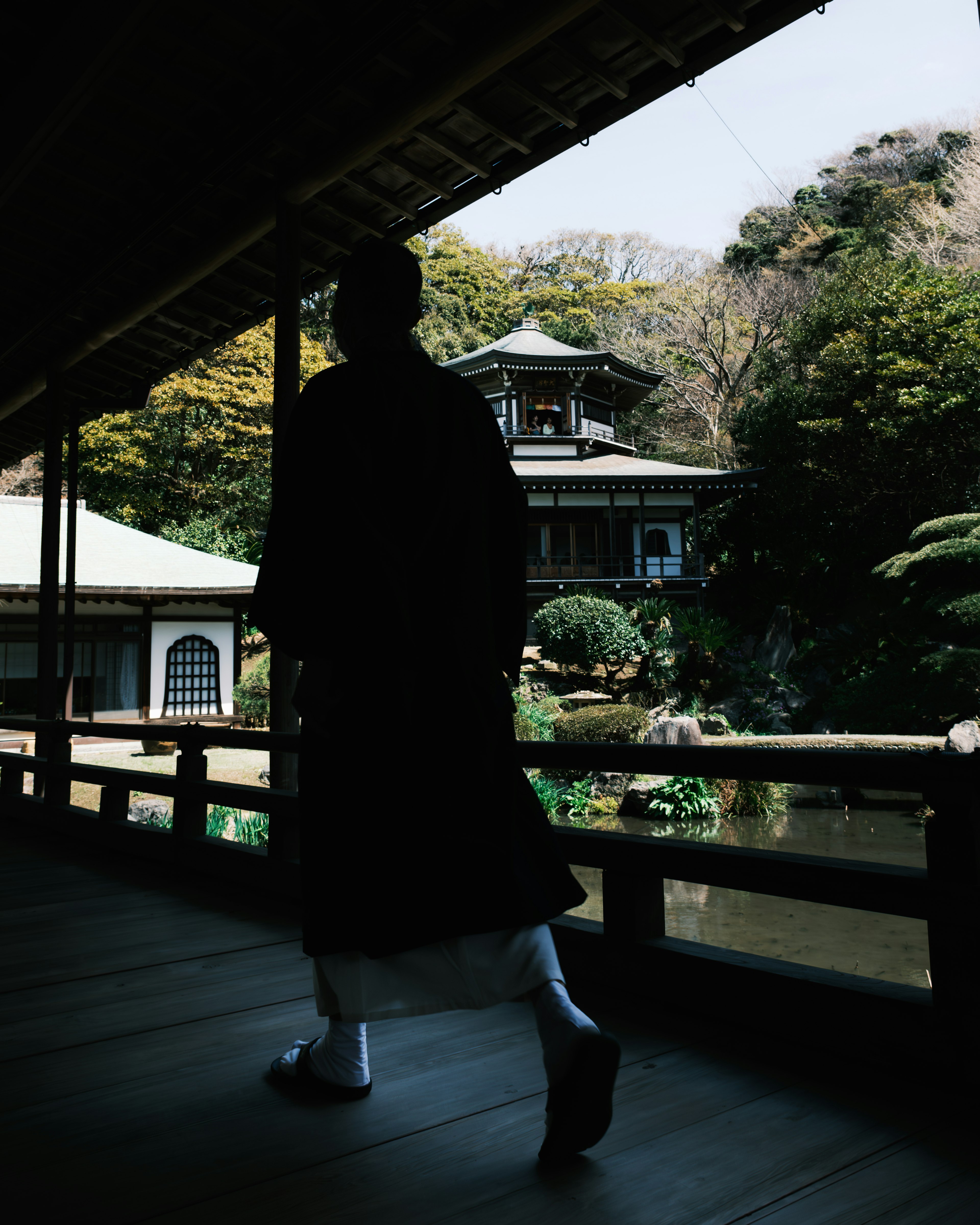 静かな庭園を歩く人物と伝統的な建物のシルエット