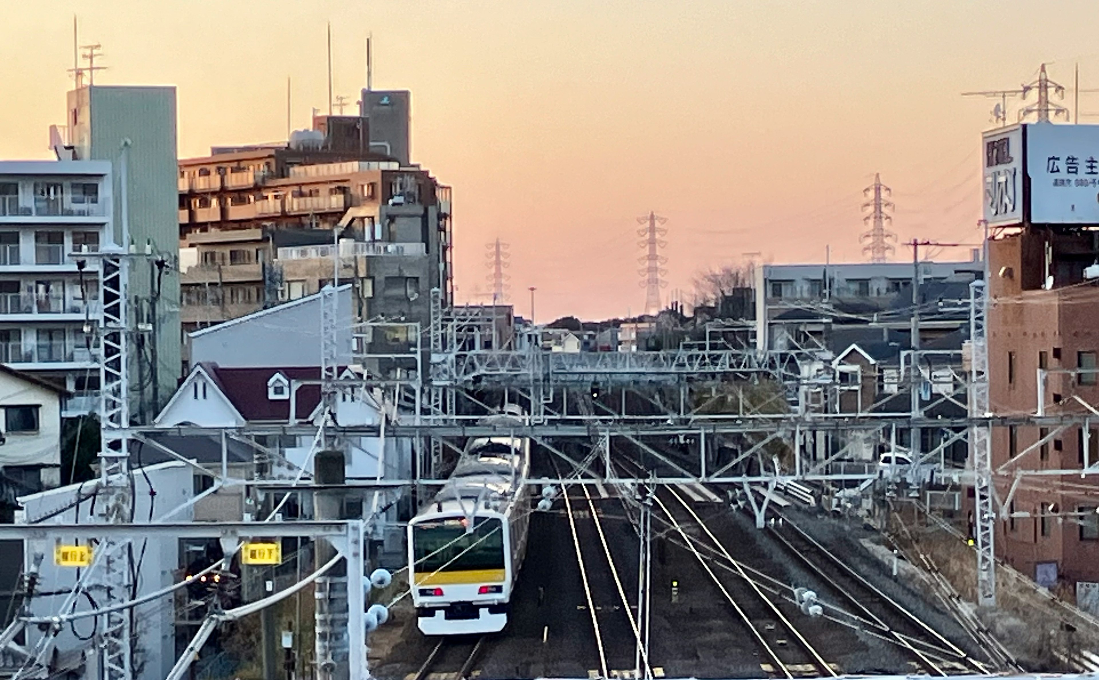 夕焼けの中を走る電車と周囲の建物が見える都市の風景