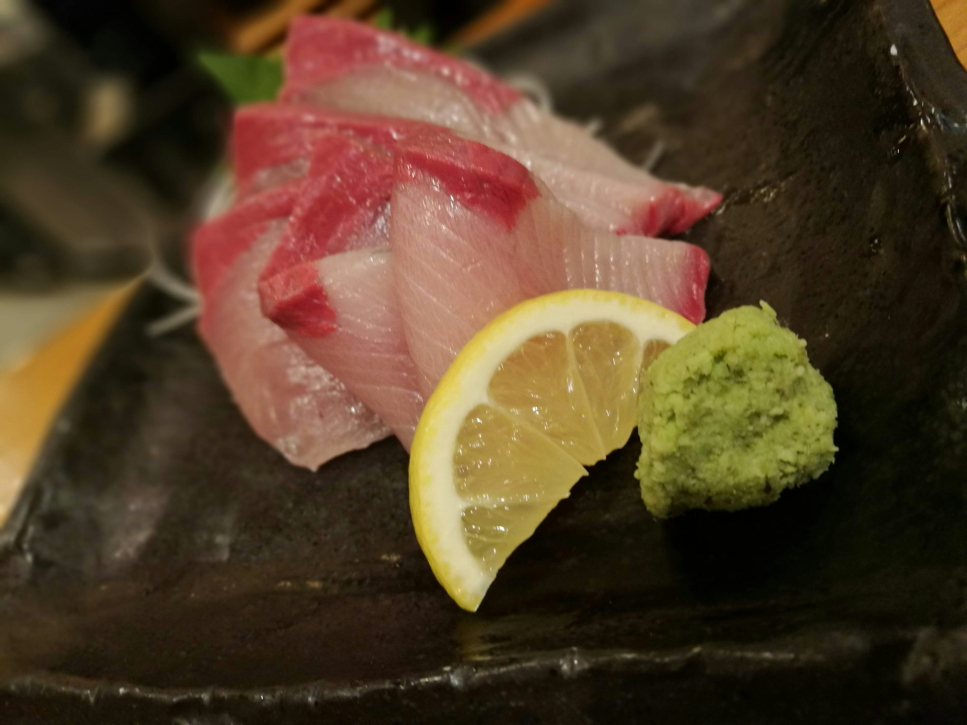 Sashimi-Platte mit dünn geschnittenem Fisch, Zitrone und Wasabi