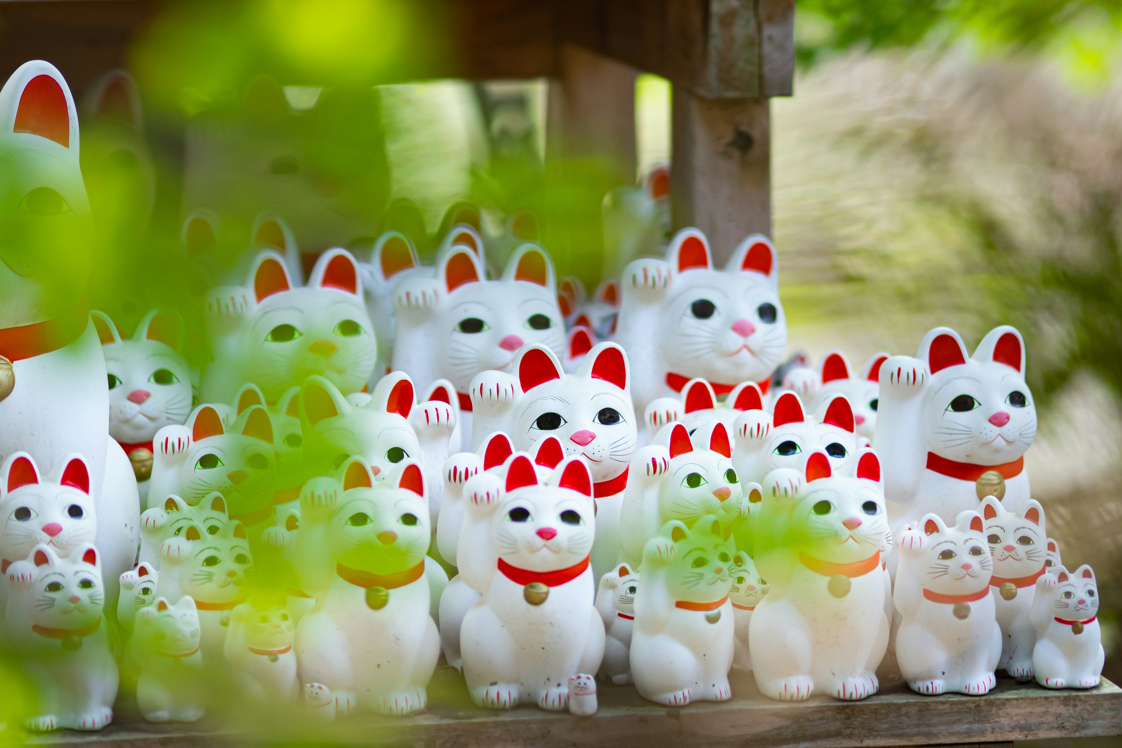 A row of white cat figurines with red accents featuring cat ears