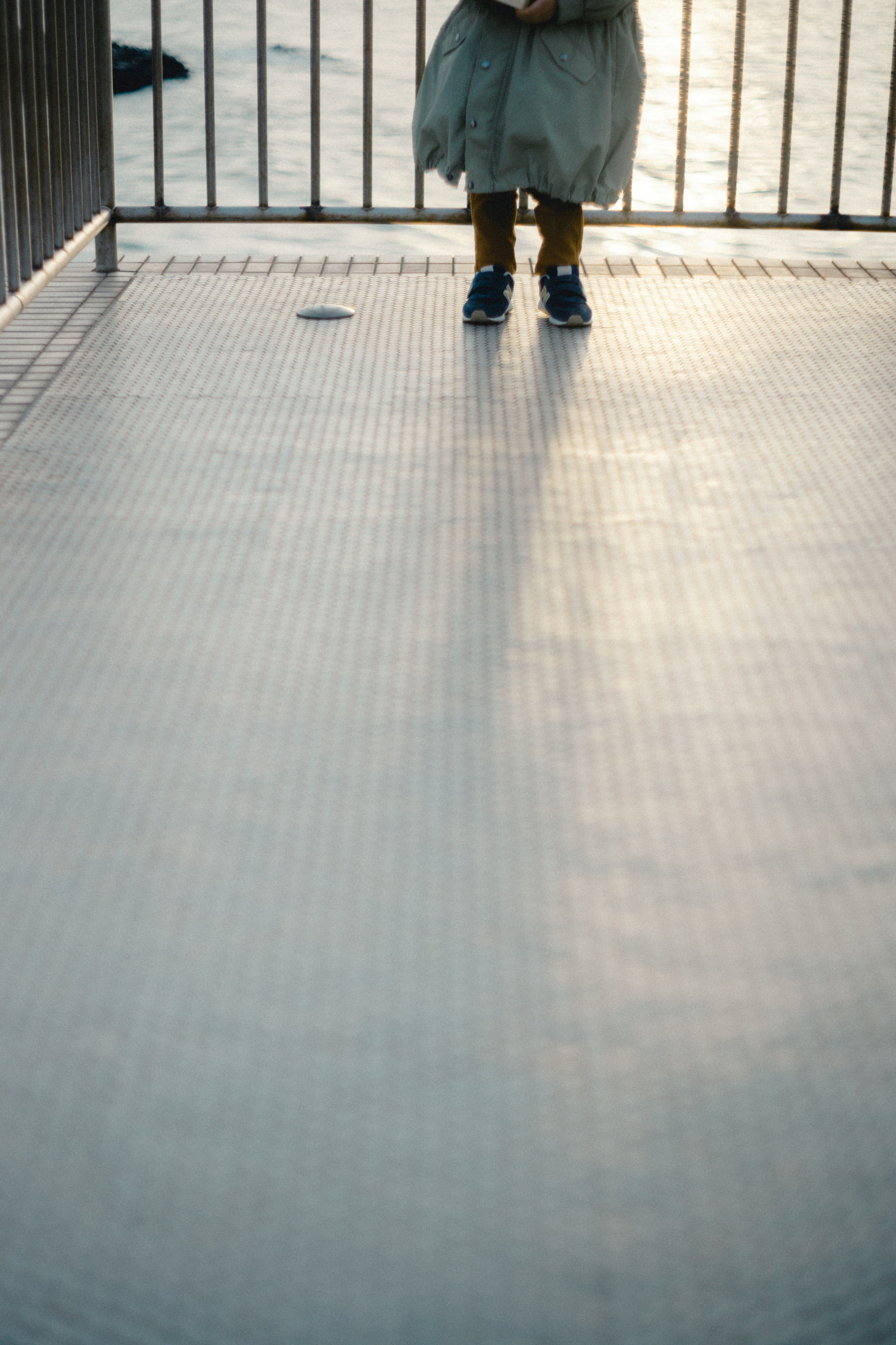 Person's feet standing on a textured surface with shadows