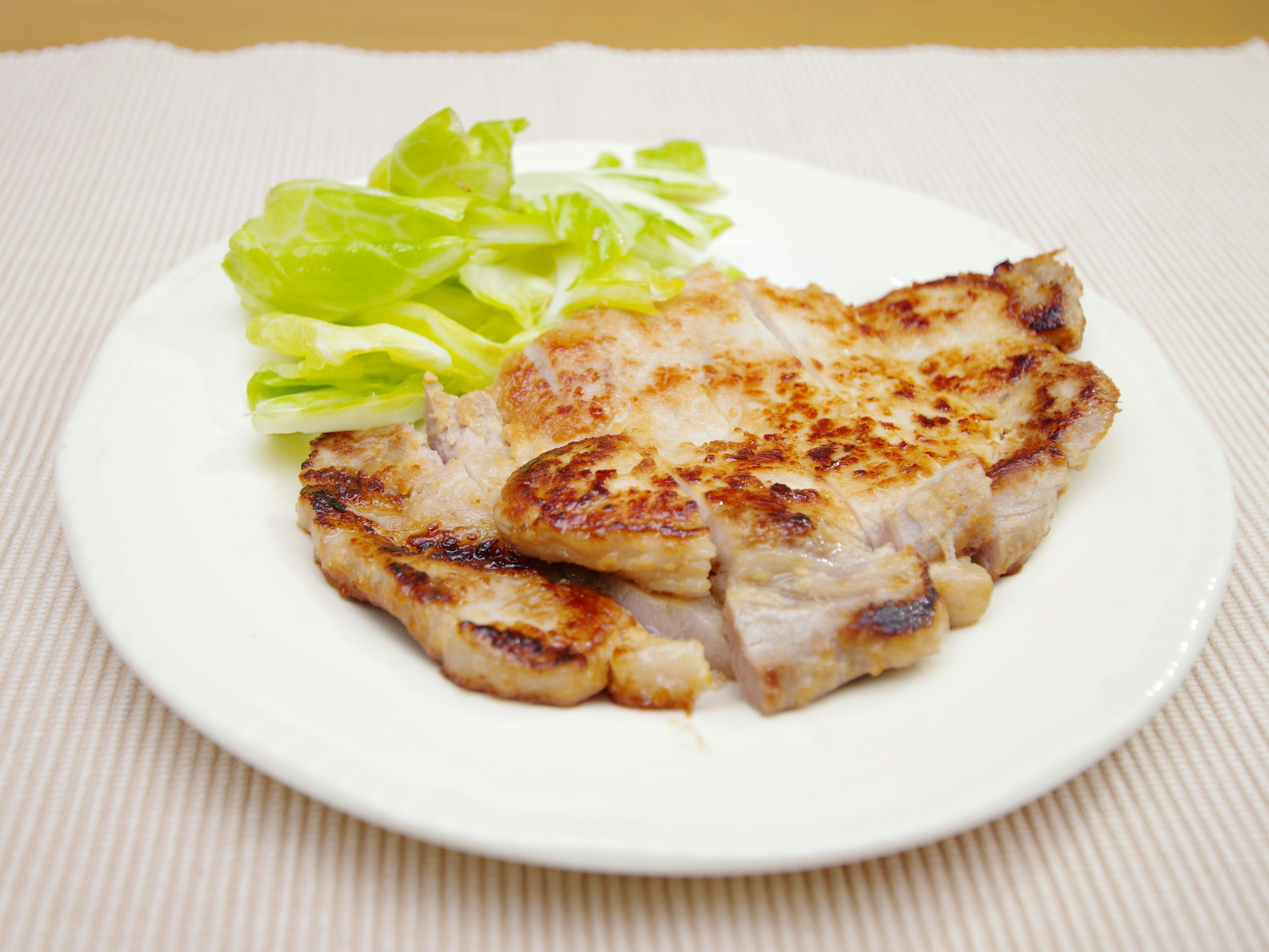 Grilled pork steak served with a side of lettuce