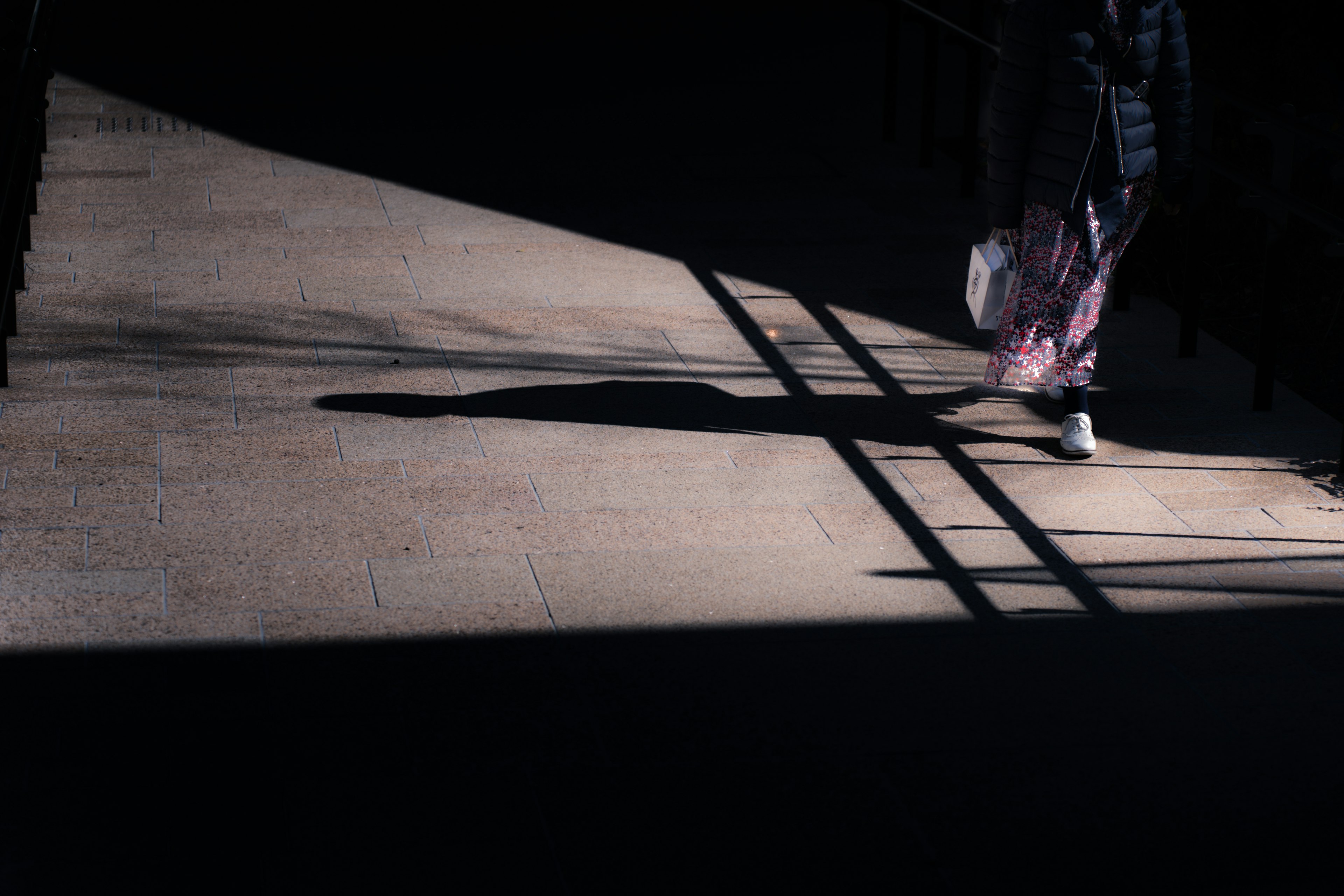 Silhouette pejalan kaki yang berjalan dengan bayangan di latar belakang gelap