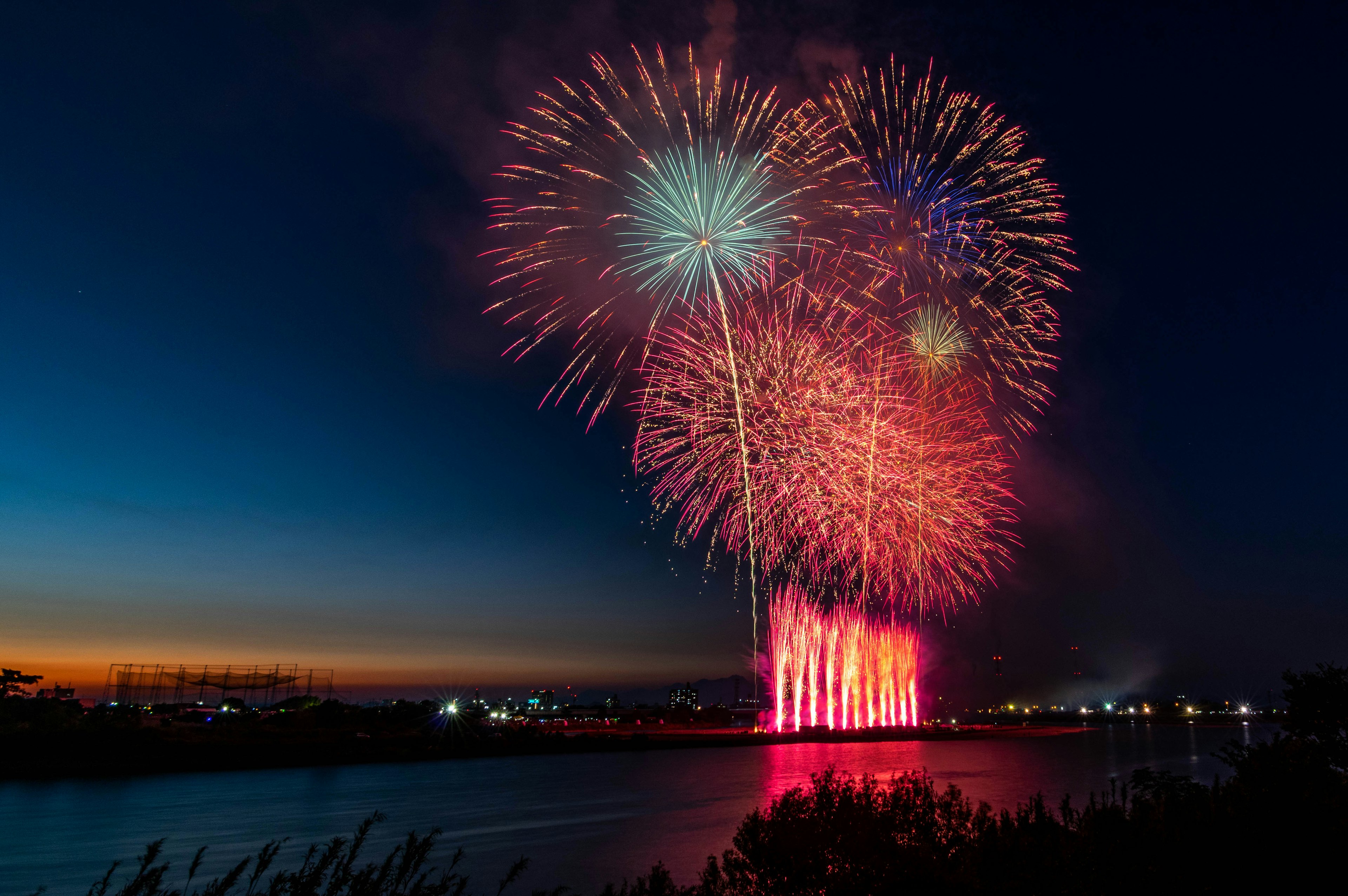 夜空中綻放的五彩煙花在河上方