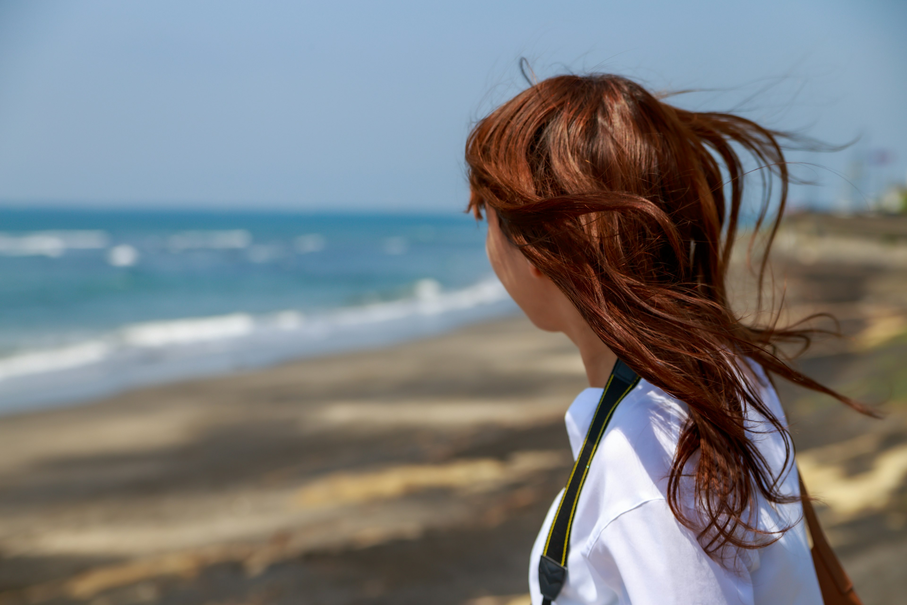 Frau, die auf den Ozean blickt, mit im Wind wehenden Haaren