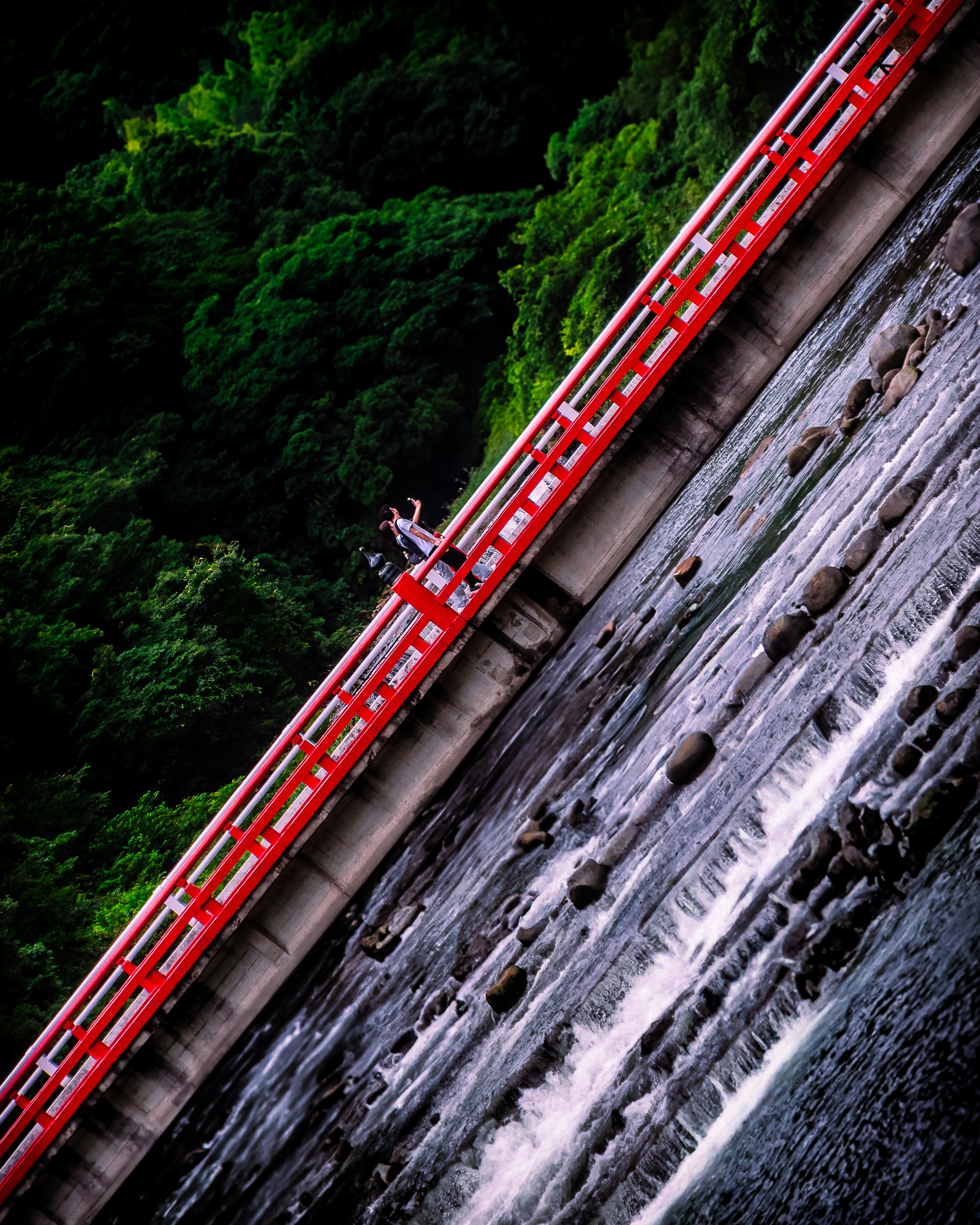 赤い橋と流れる川の景色に立つ人