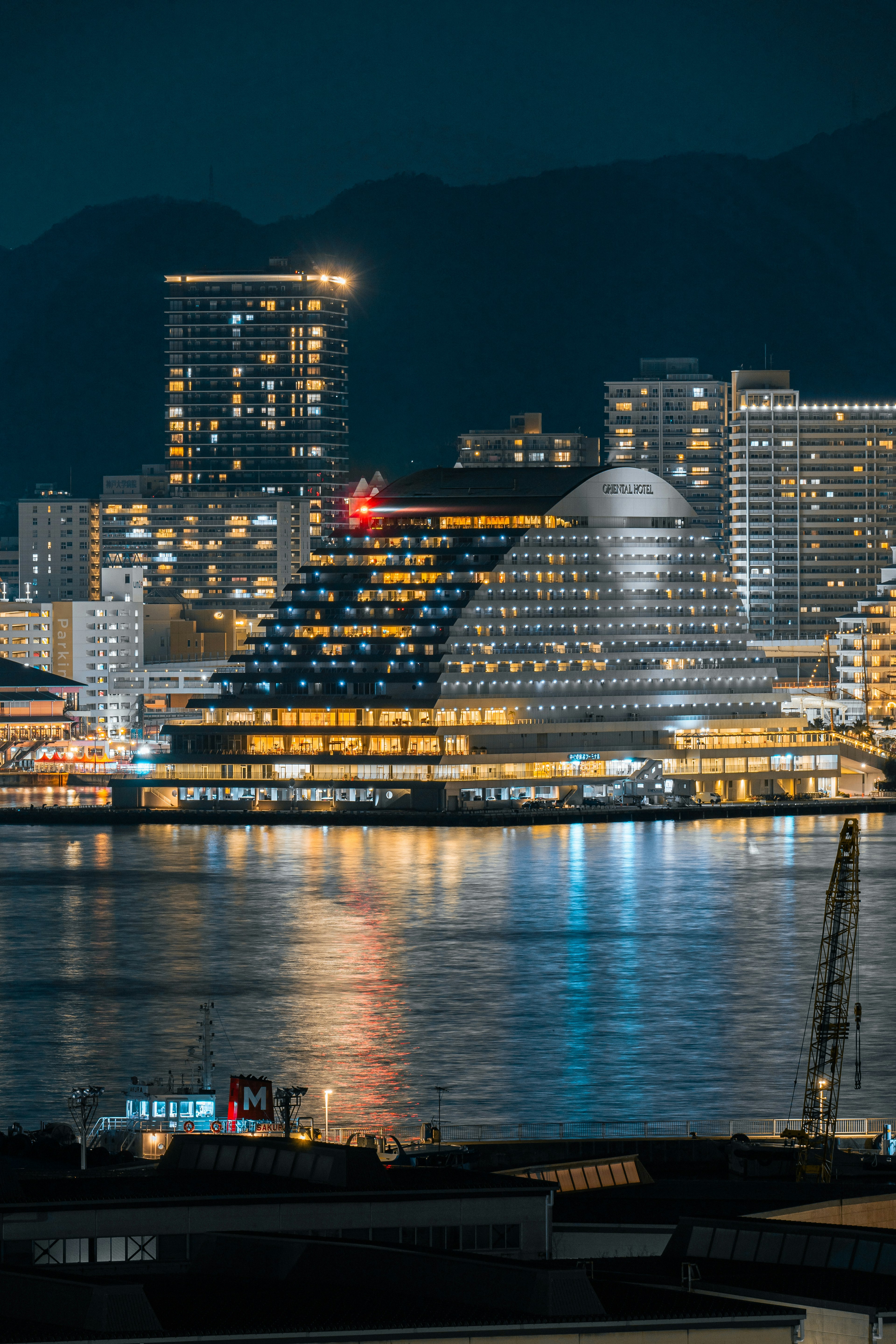 Nighttime cityscape featuring illuminated buildings and reflections on water