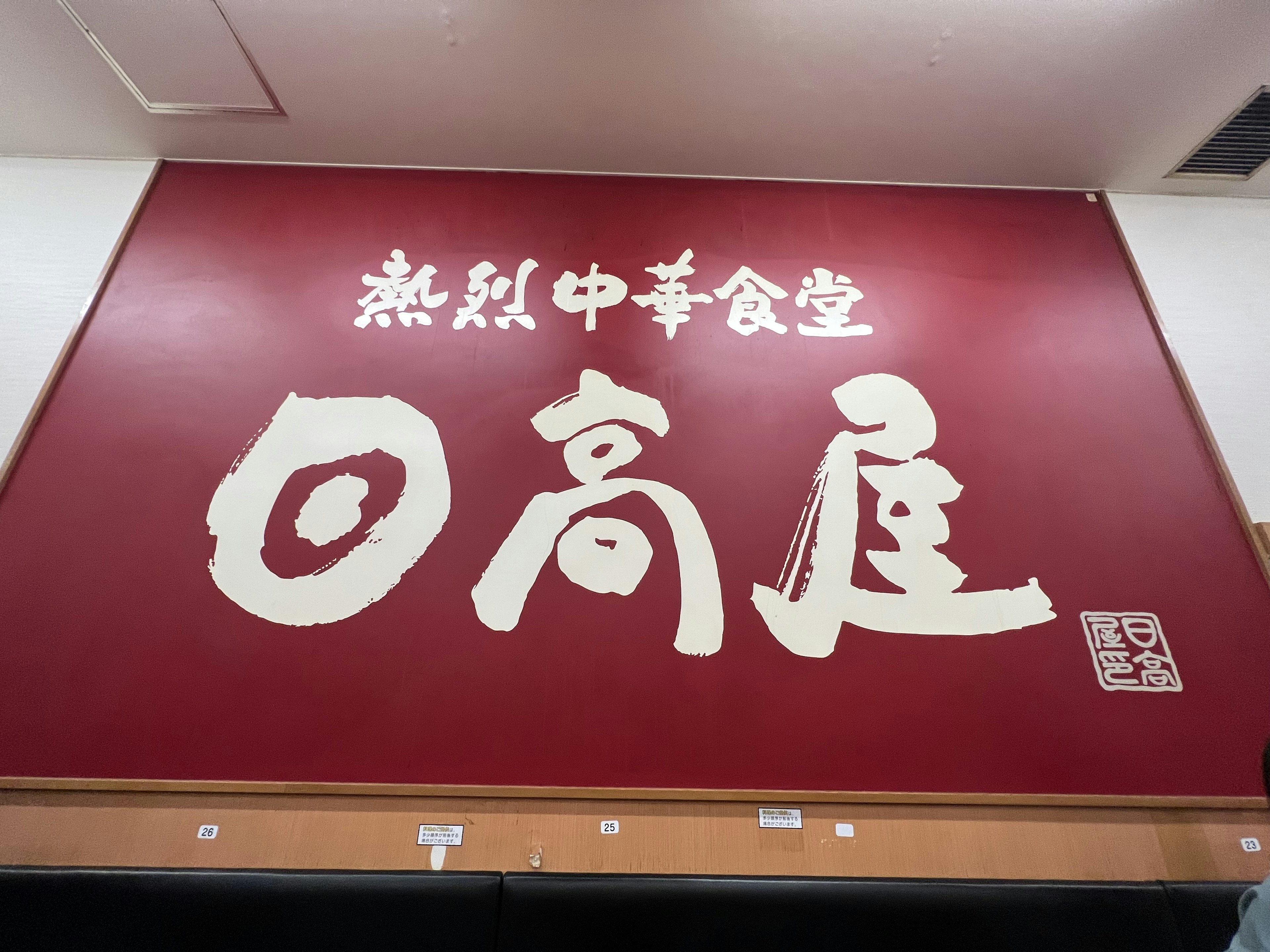 赤い壁に書かれた中国料理店の看板には大きくて太い文字で店名が書かれている