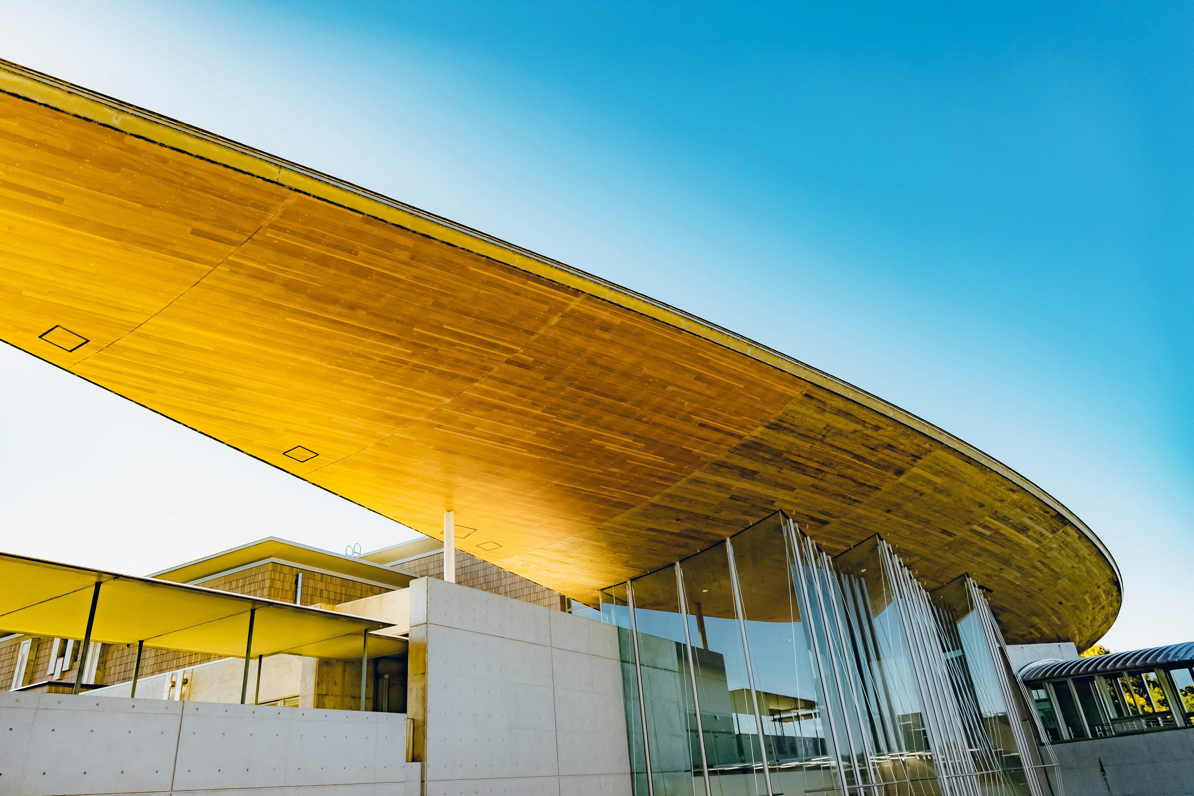 Modern architectural structure with a wooden roof and glass facade