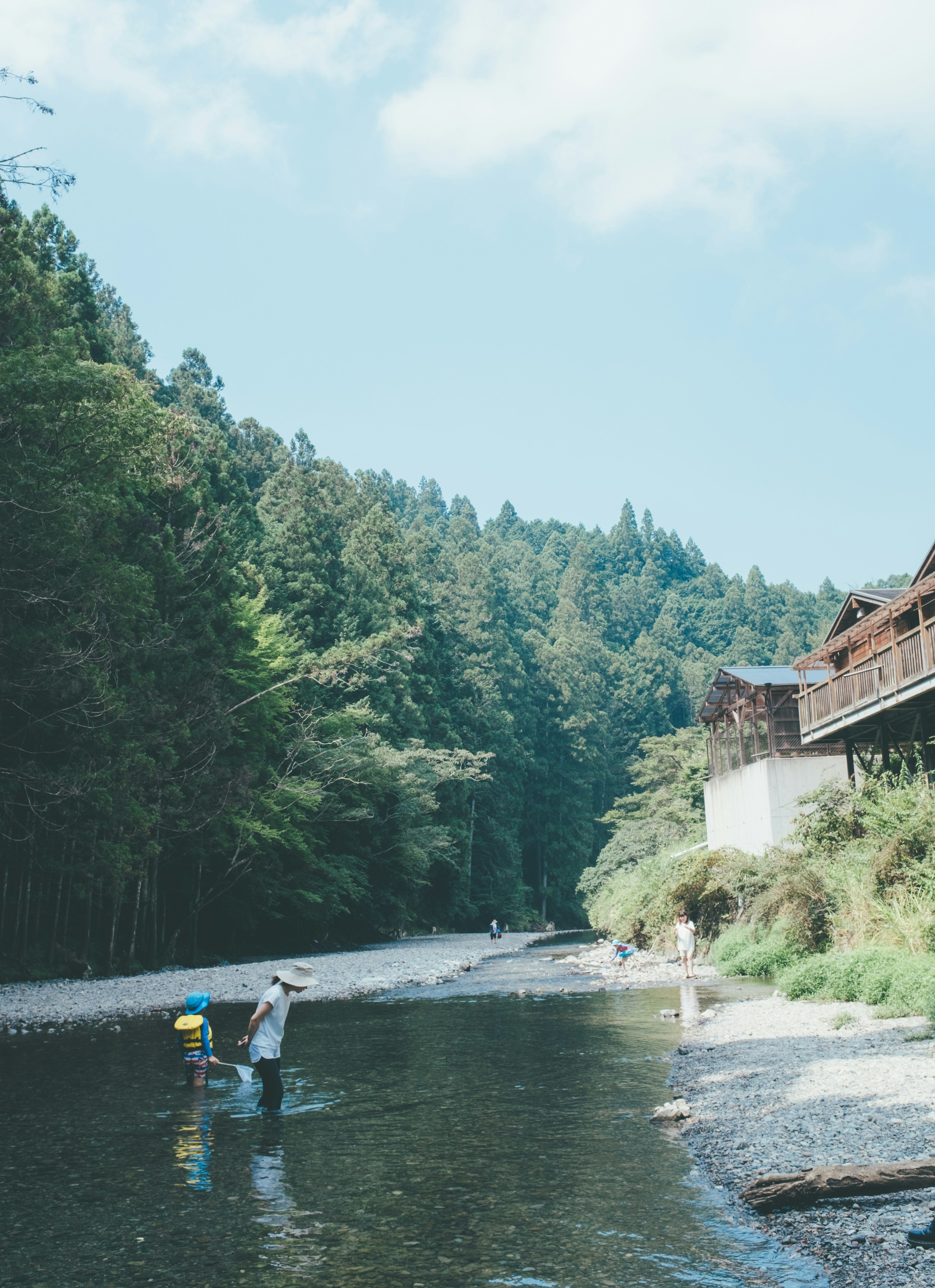 静かな川で釣りをする人々と緑豊かな山々の風景