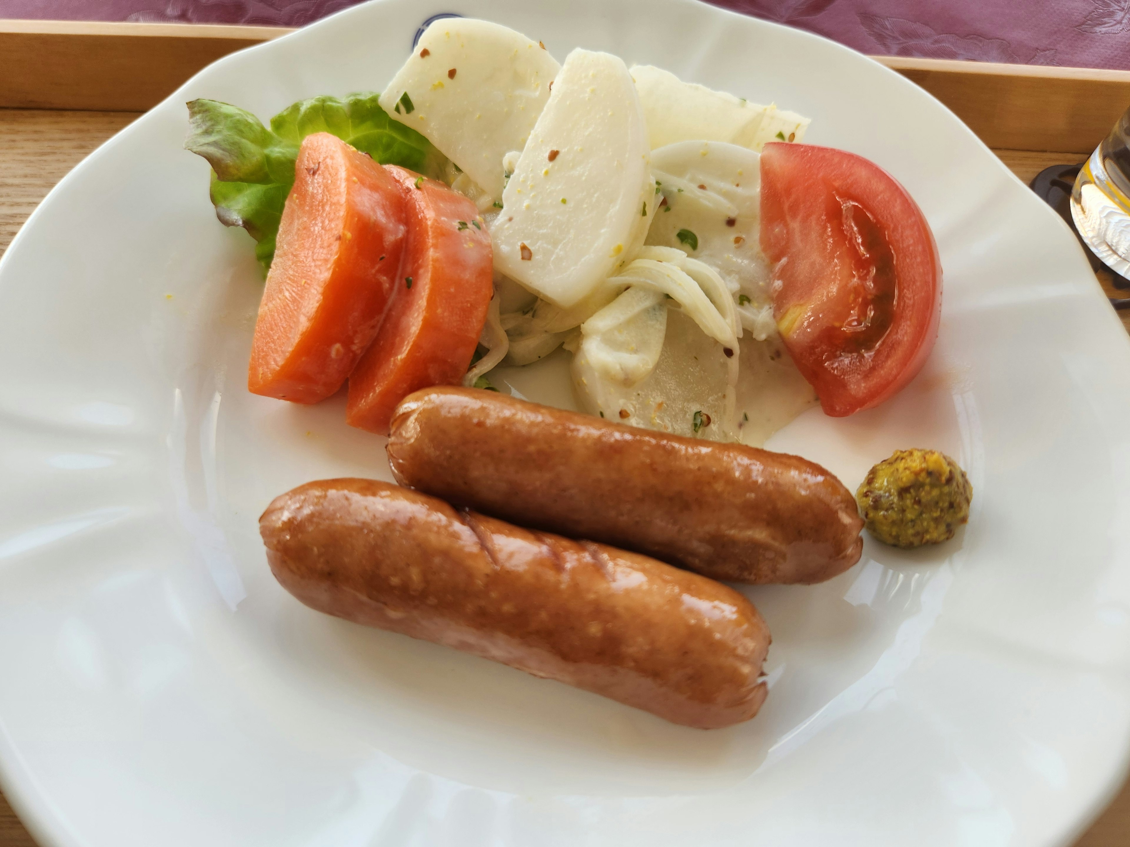 Teller mit Würstchen und frischem Salat mit Tomaten und Salat