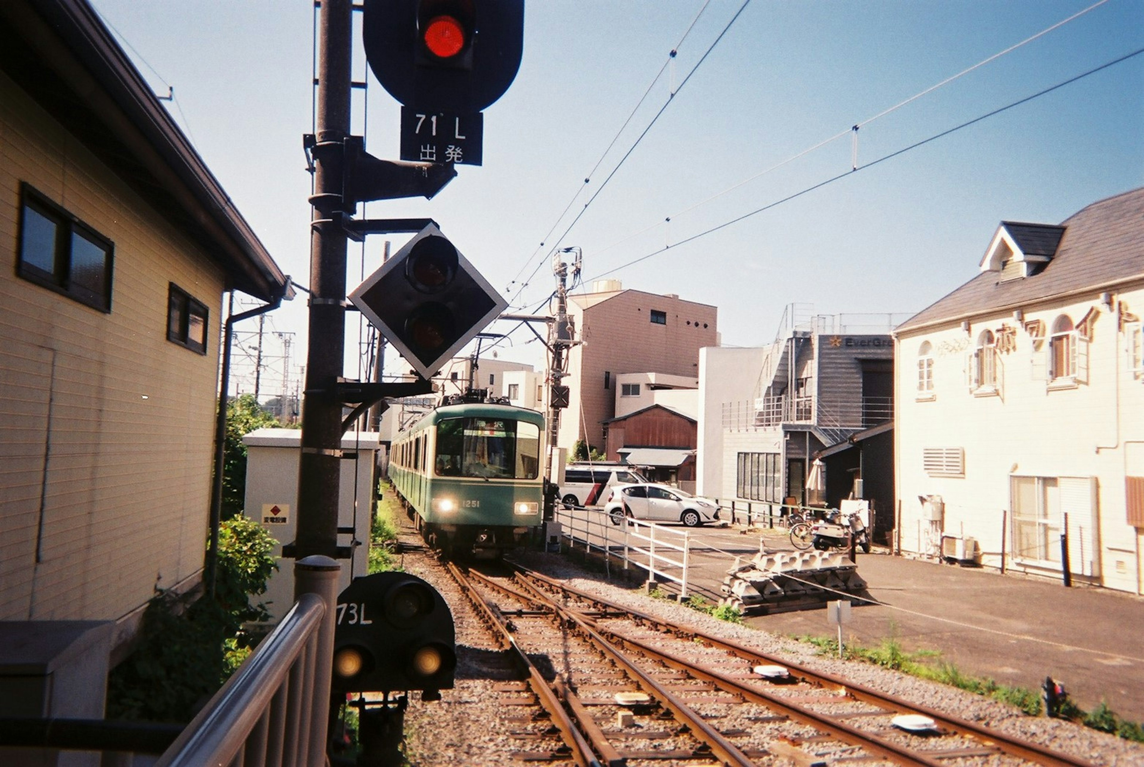 赤信号の前を通過する電車と周囲の建物が写った風景