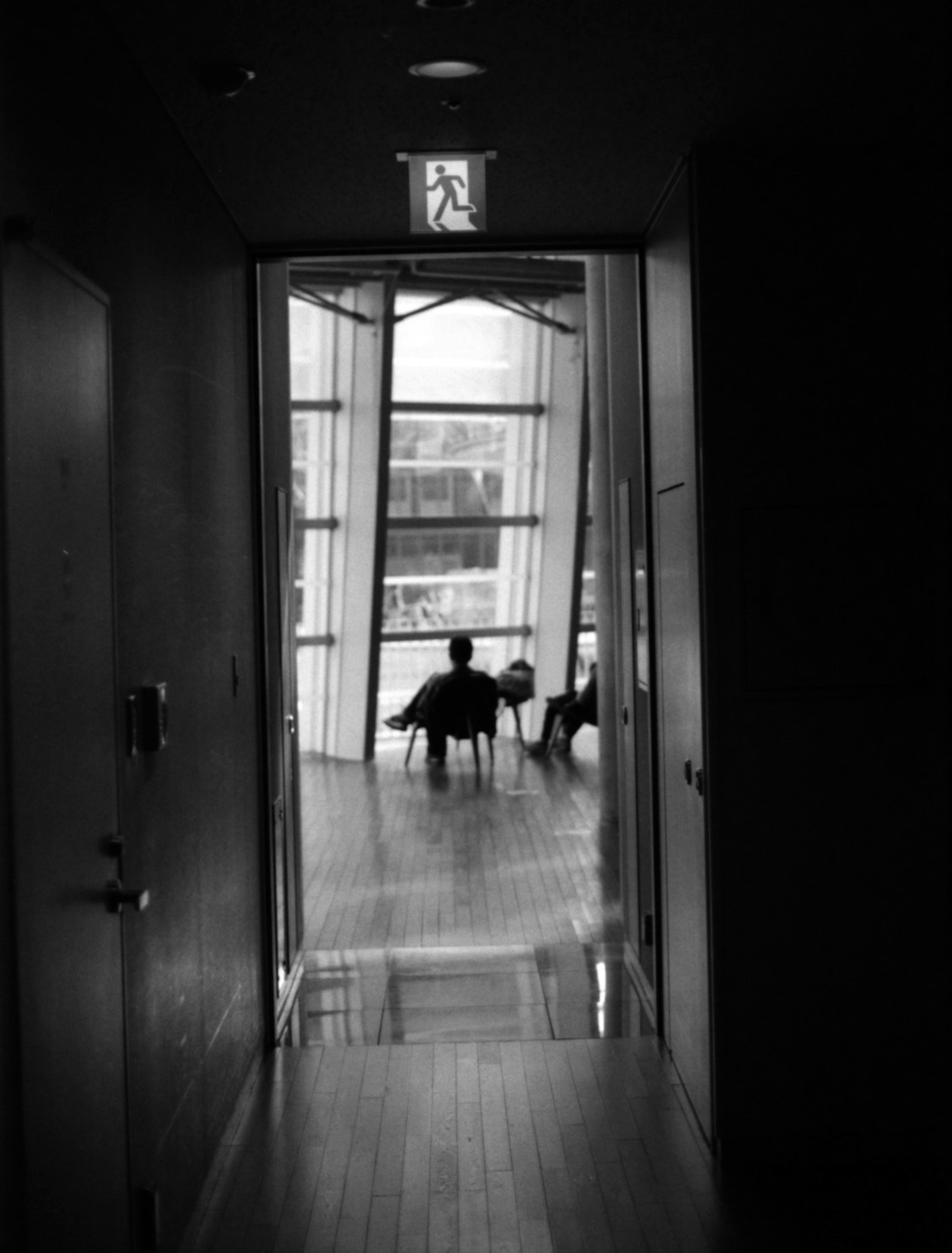 Silhouette d'une personne assise dans un espace lumineux au bout d'un couloir sombre