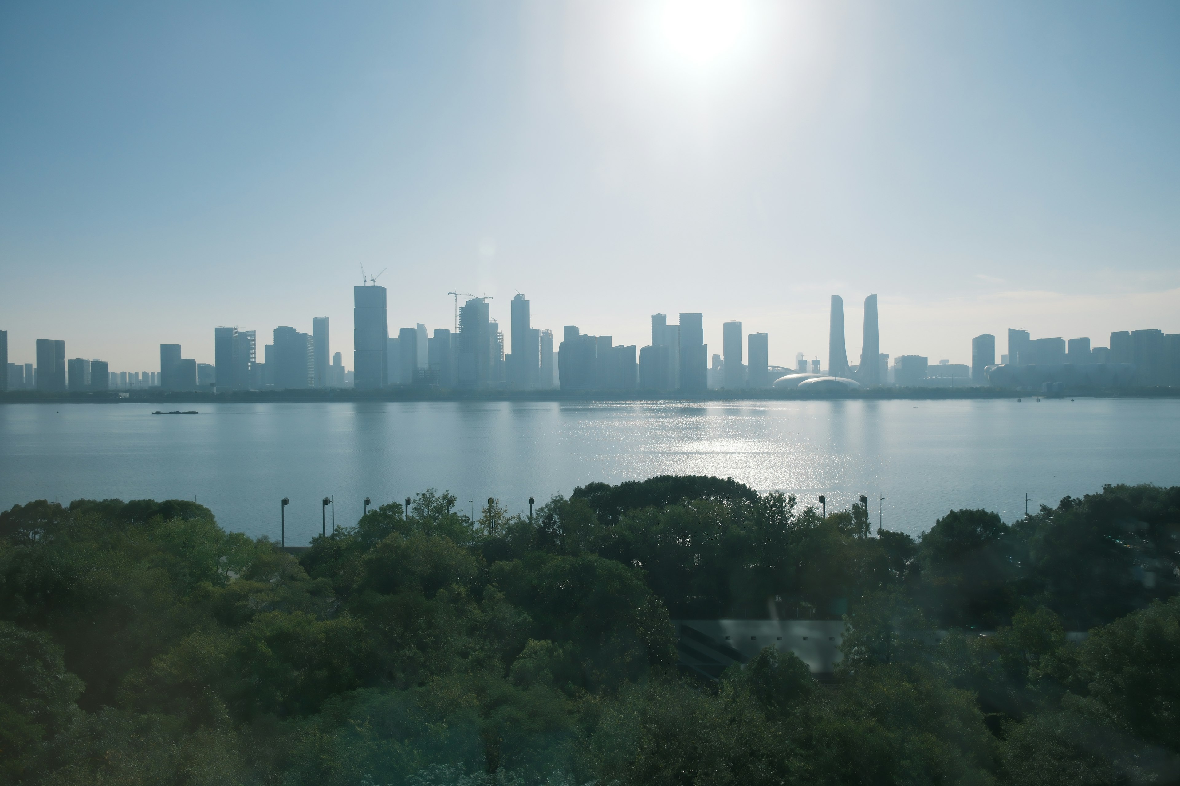 City skyline under a bright sun with reflections on the water