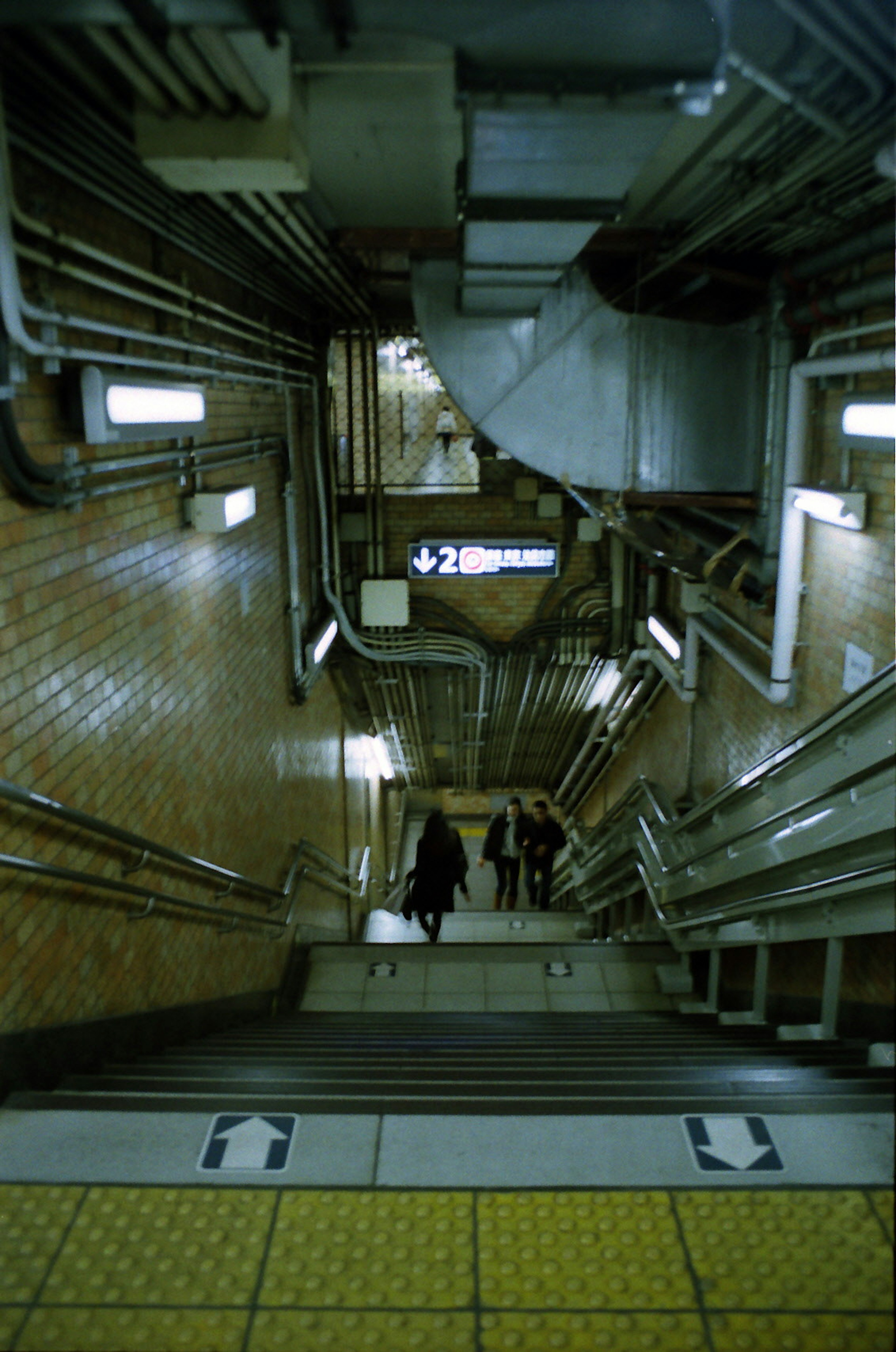 Vista dalla scala di una stazione della metropolitana con corrimano illuminati e pavimento piastrellato