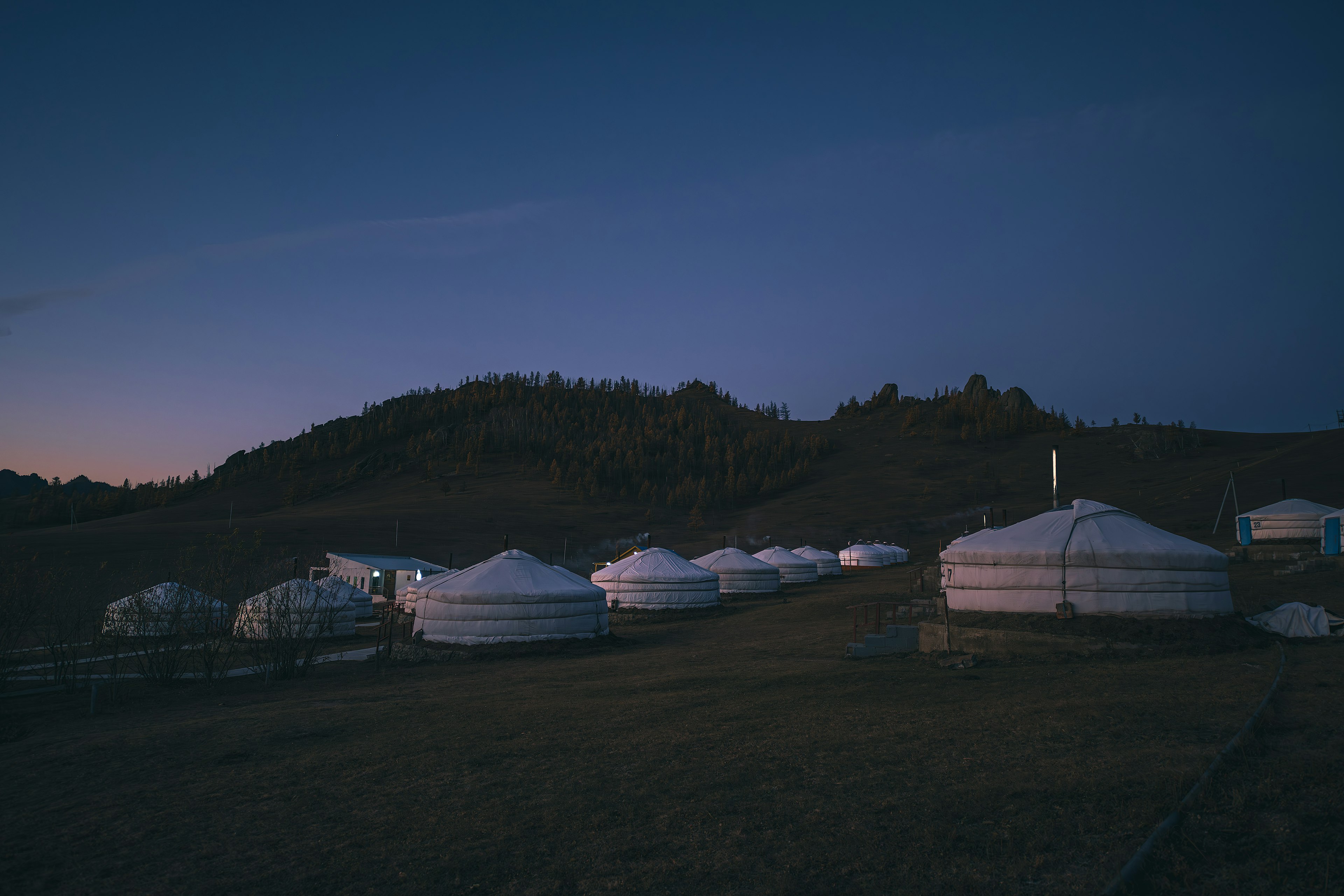 Yurts arranged in a grassy landscape during twilight