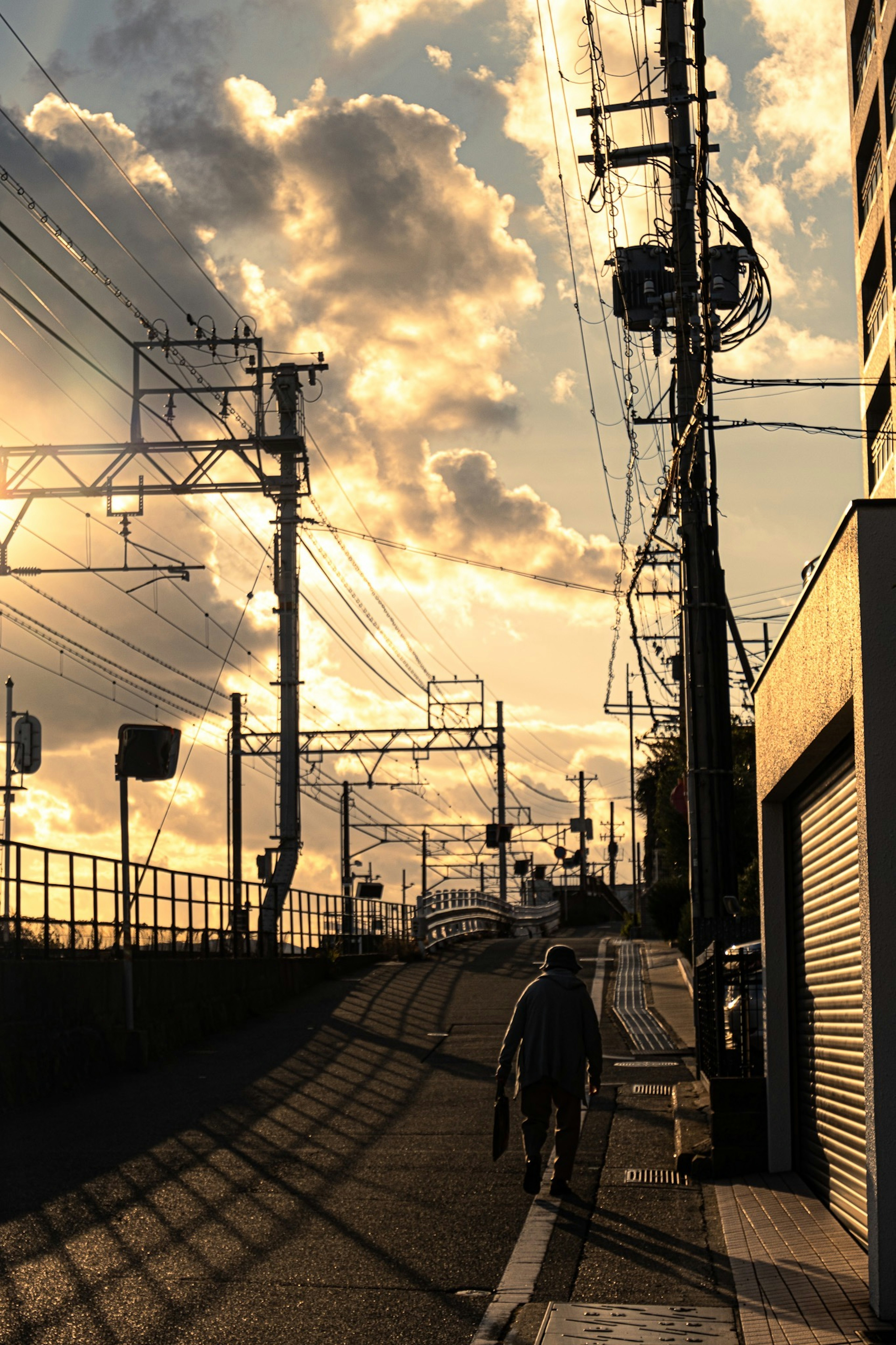 夕暮れ時の街道を歩く人影と電柱のシルエット