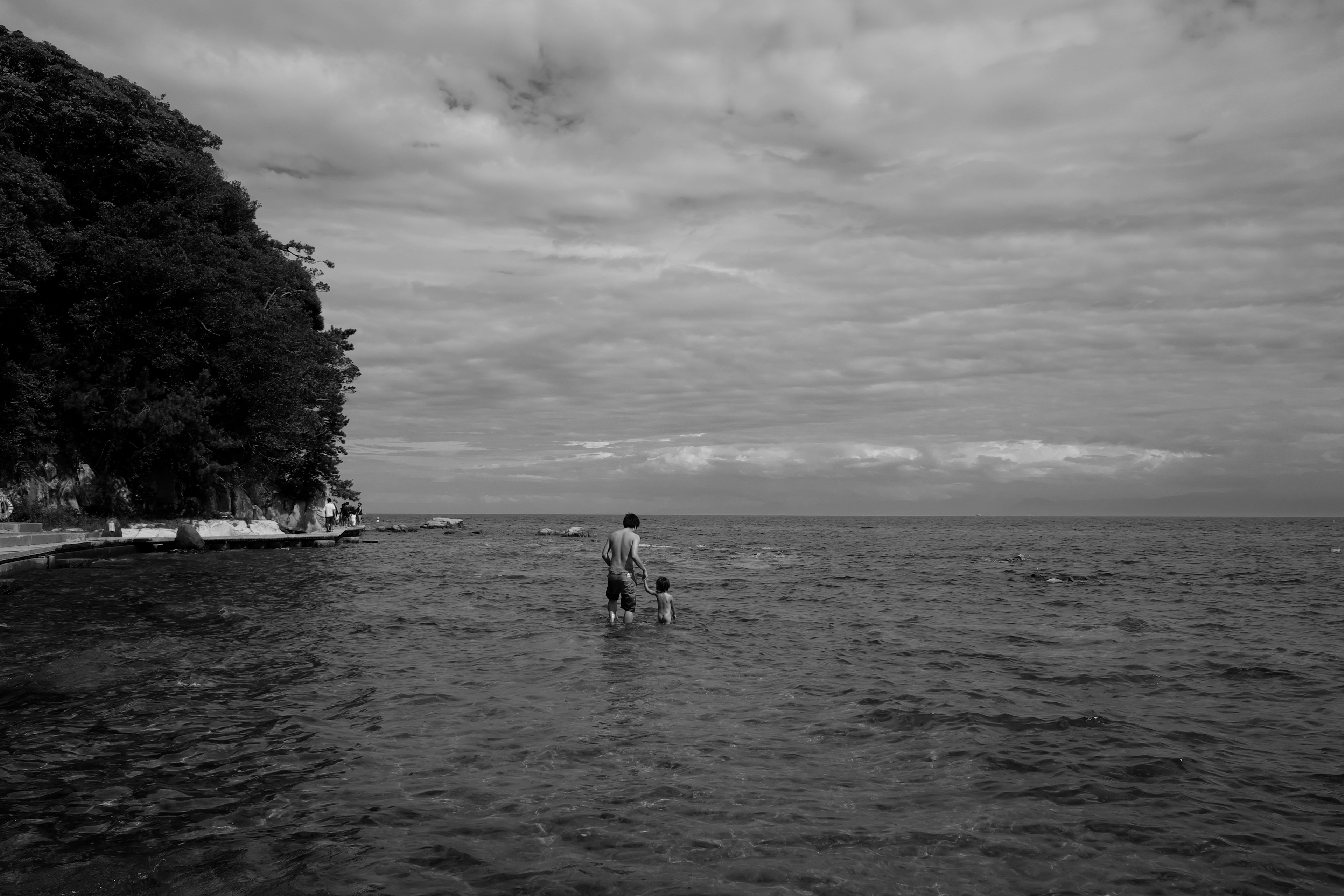 Silhouette of a parent and child playing in the sea black and white landscape calm sky