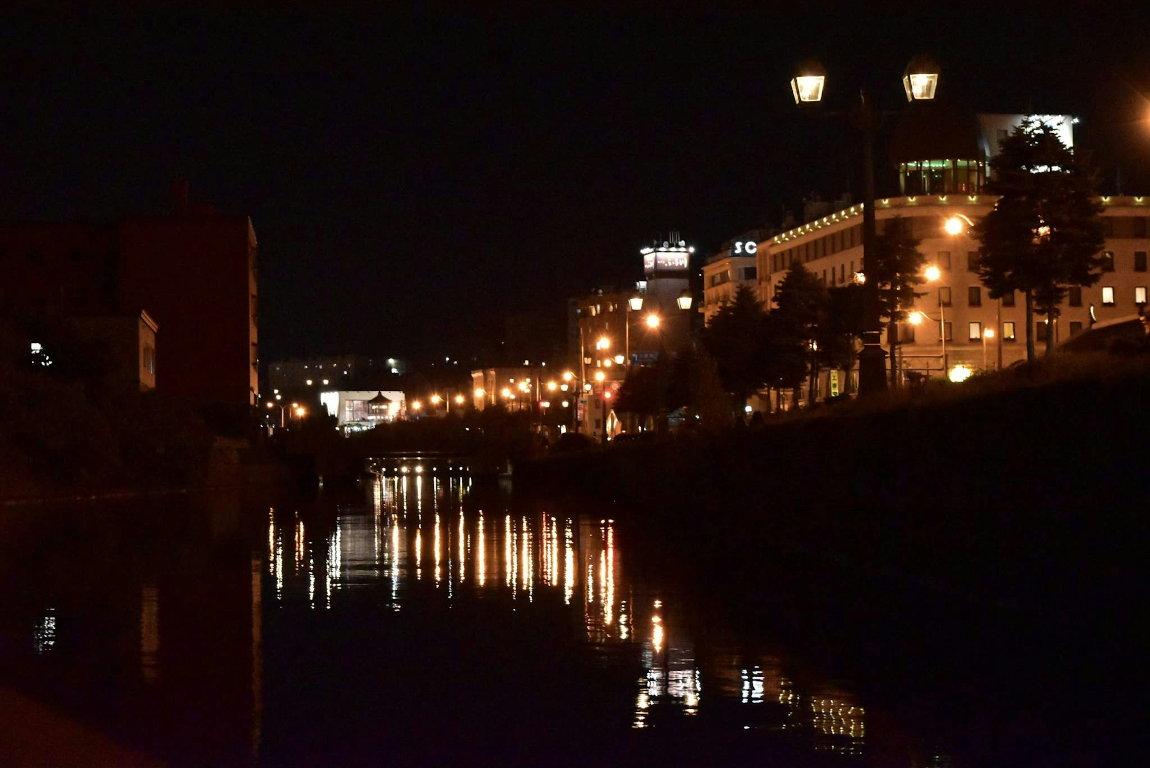 Vista nocturna de un río con edificios iluminados y reflejos