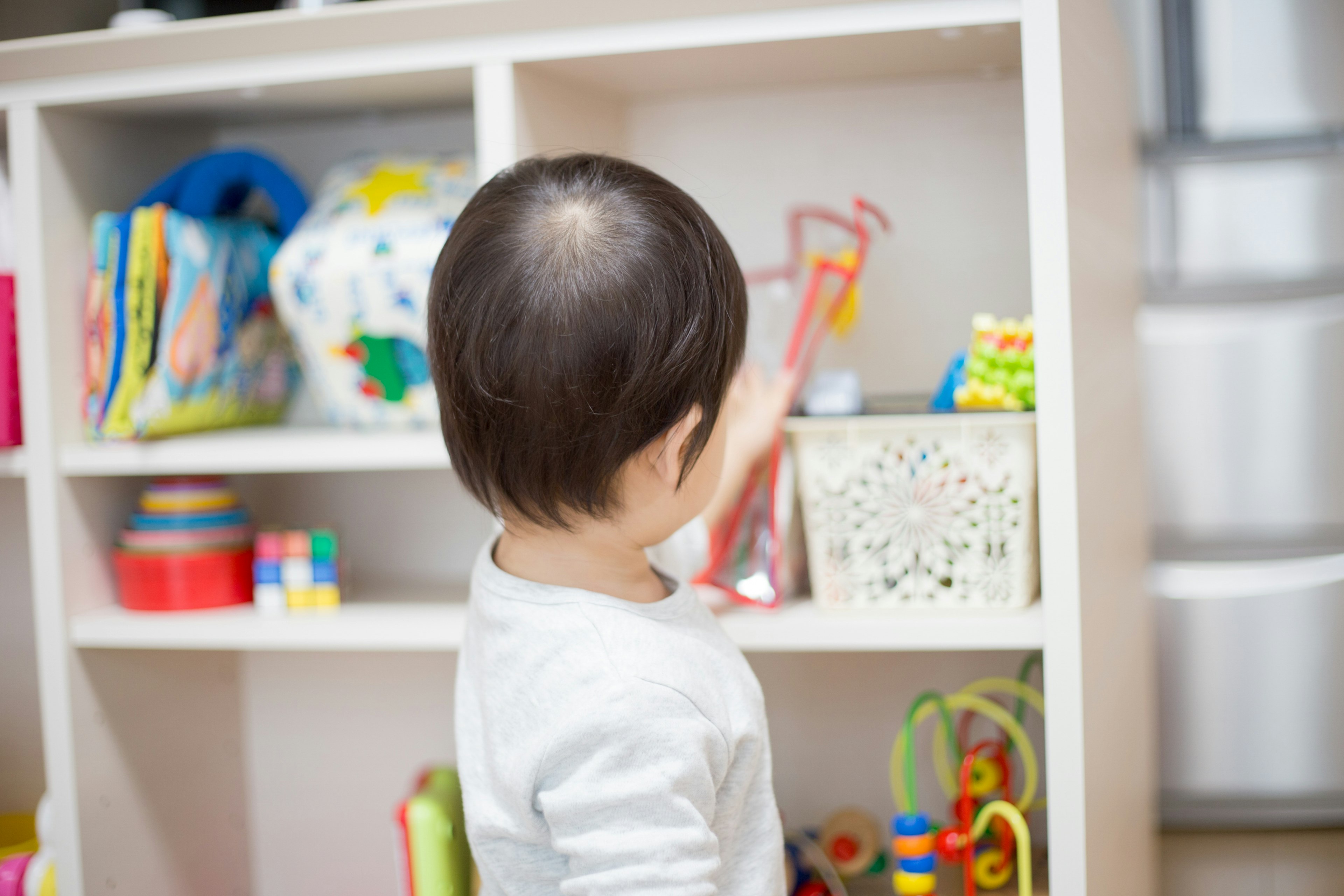 Bambino che guarda una libreria di giocattoli di spalle