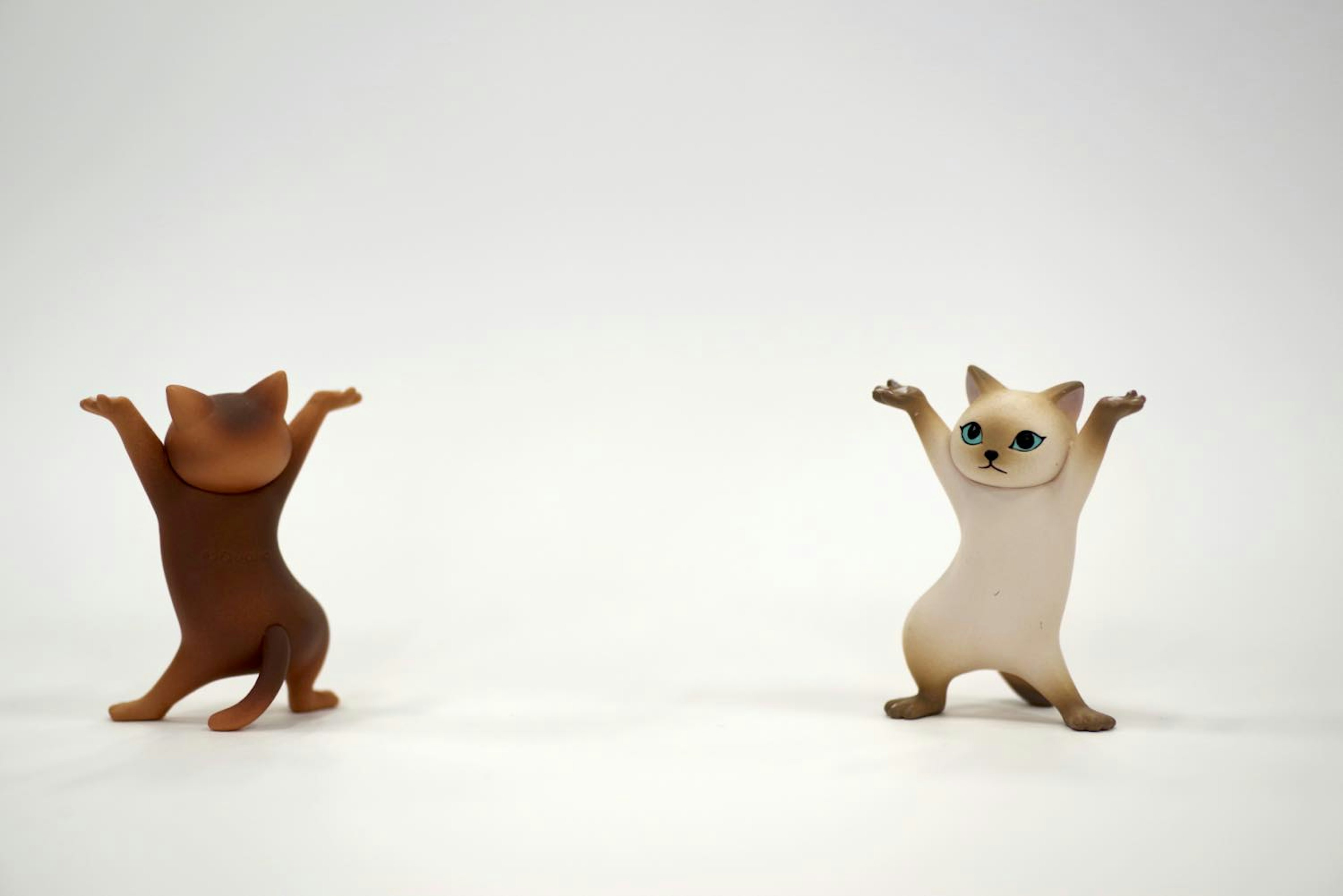 Two cute cat figurines raising their arms